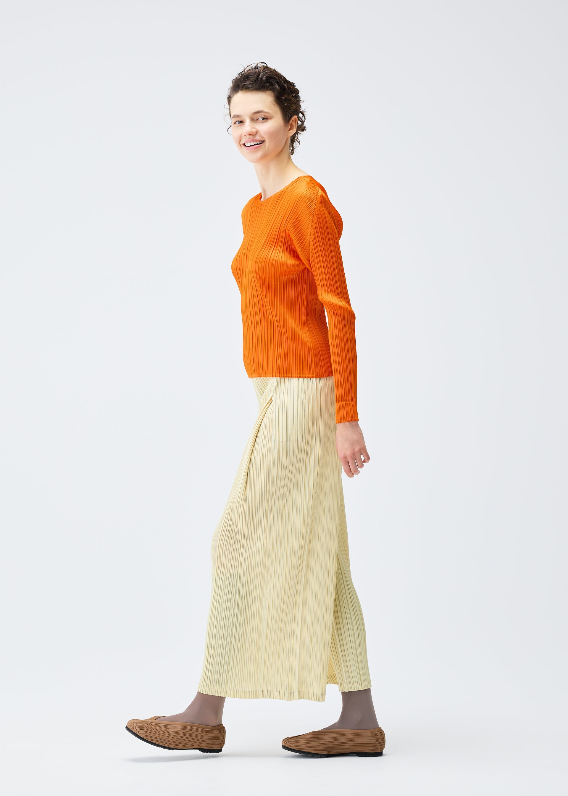 A model wears the PLEATS PLEASE ISSEY MIYAKE MONTHLY COLORS DECEMBER clothing.