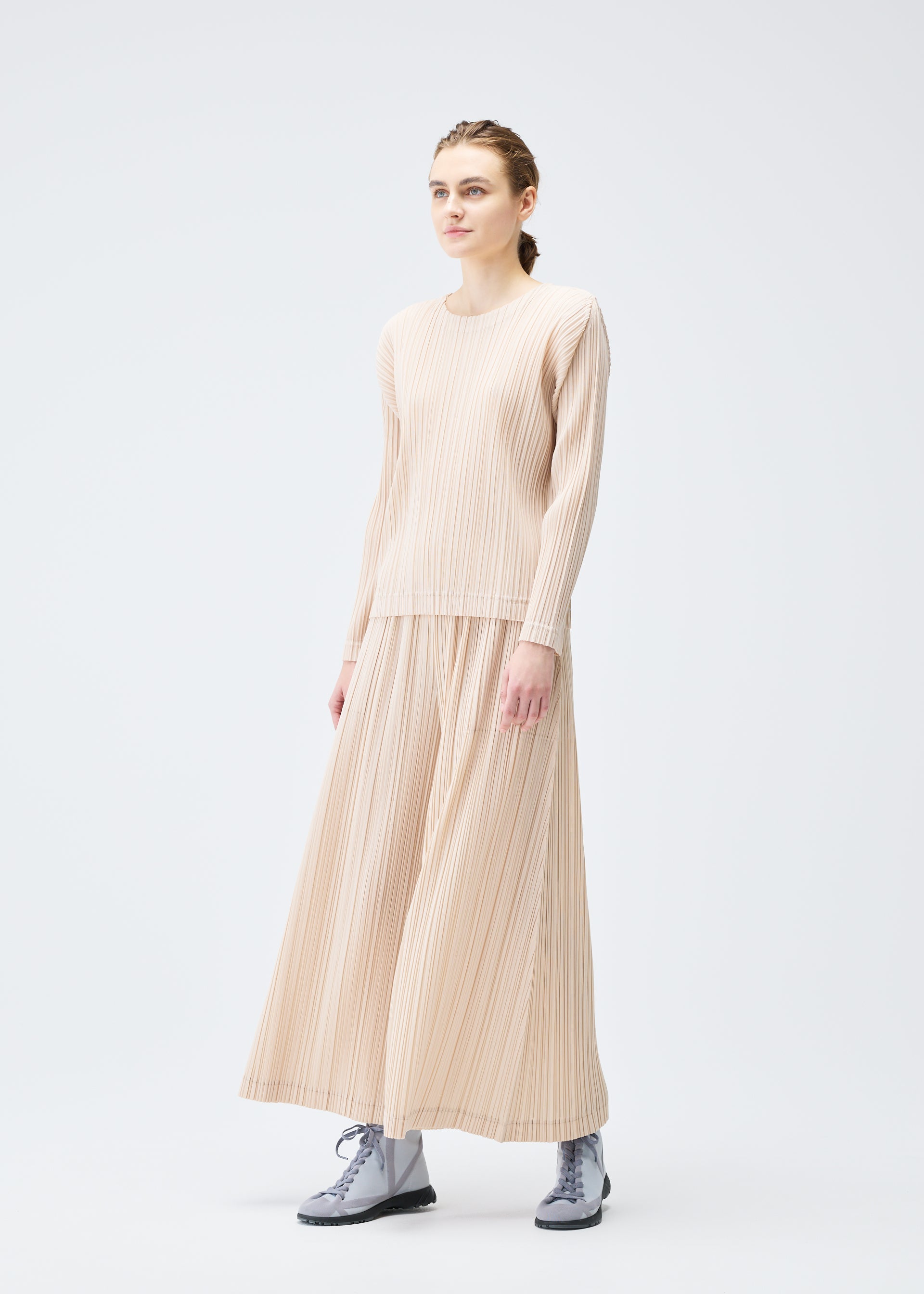 A model wears the PLEATS PLEASE ISSEY MIYAKE WOOL PLEATS trousers.