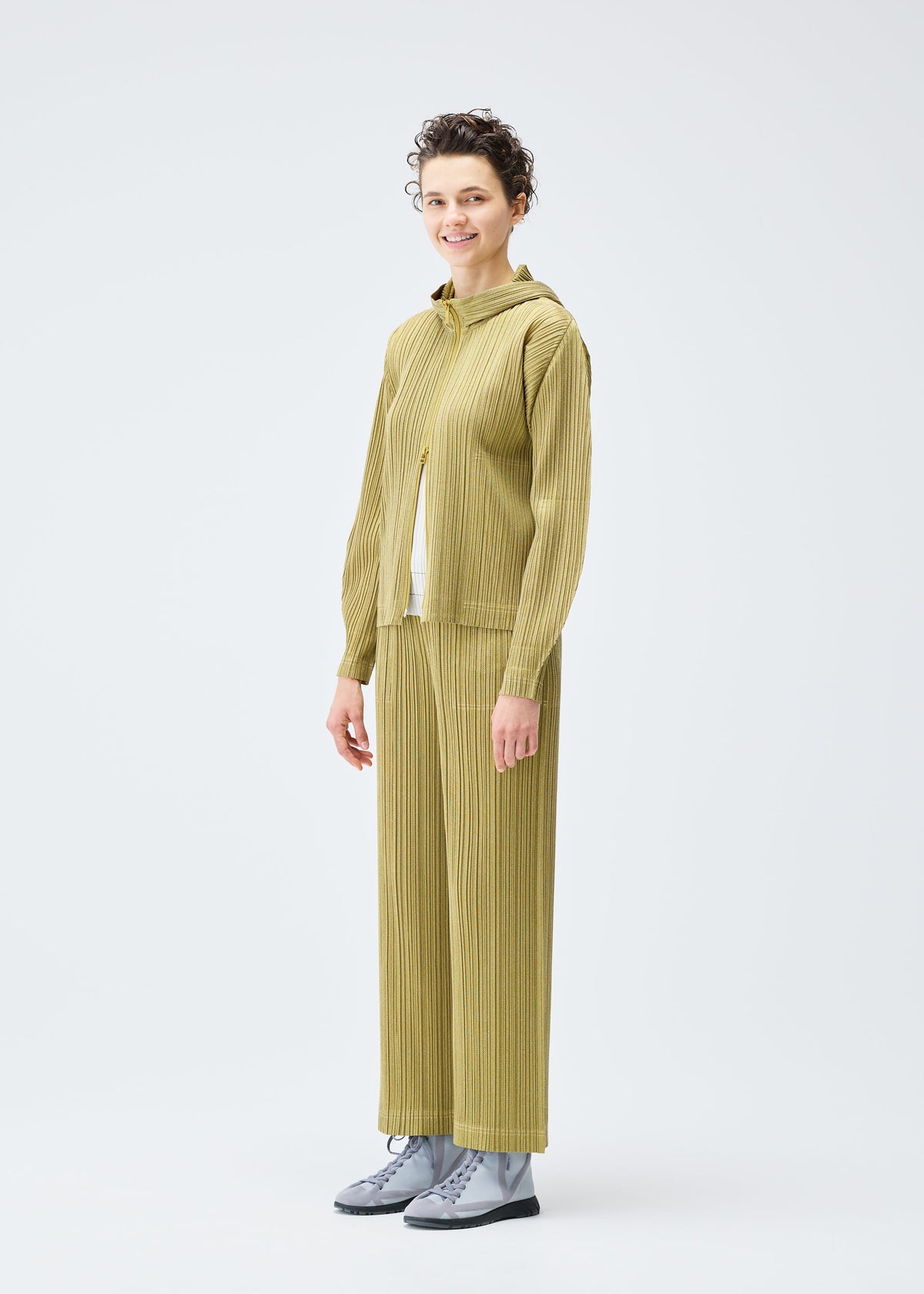 A model wears the PLEATS PLEASE ISSEY MIYAKE COTTON DENIM trousers.