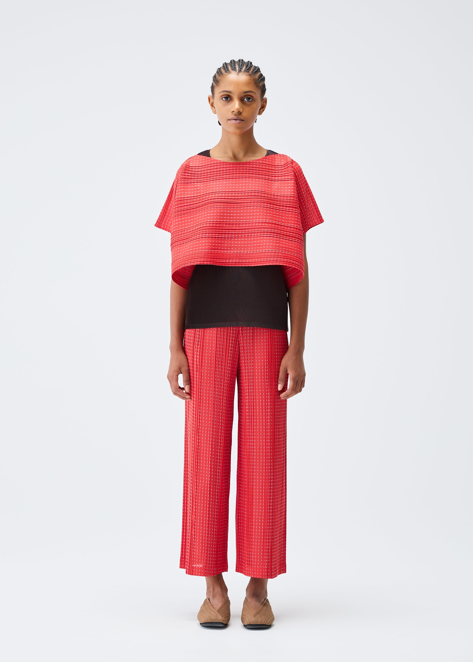 A model wears the PLEATS PLEASE ISSEY MIYAKE COTTON SKIP trousers.