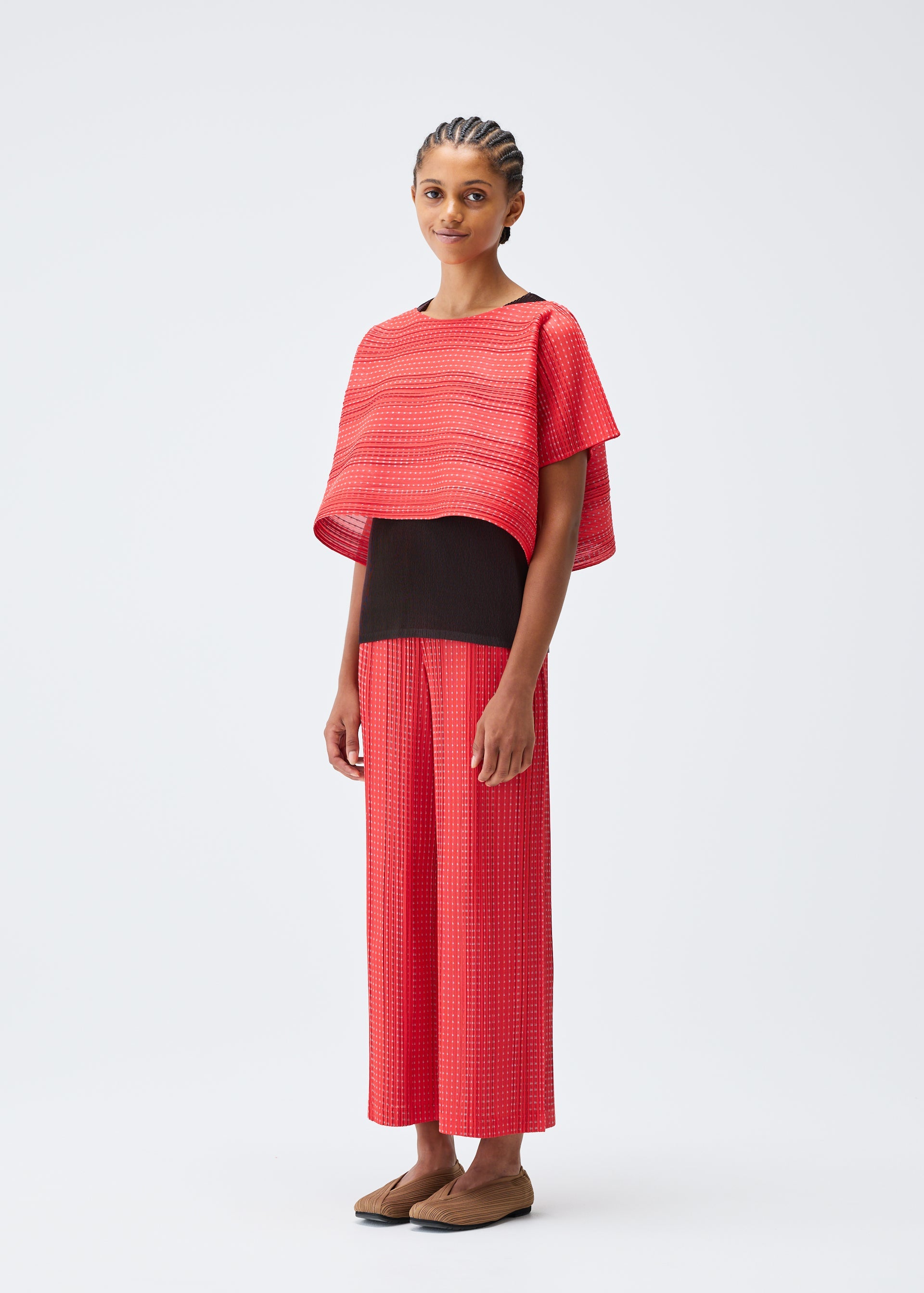 A model wears the PLEATS PLEASE ISSEY MIYAKE COTTON SKIP trousers.