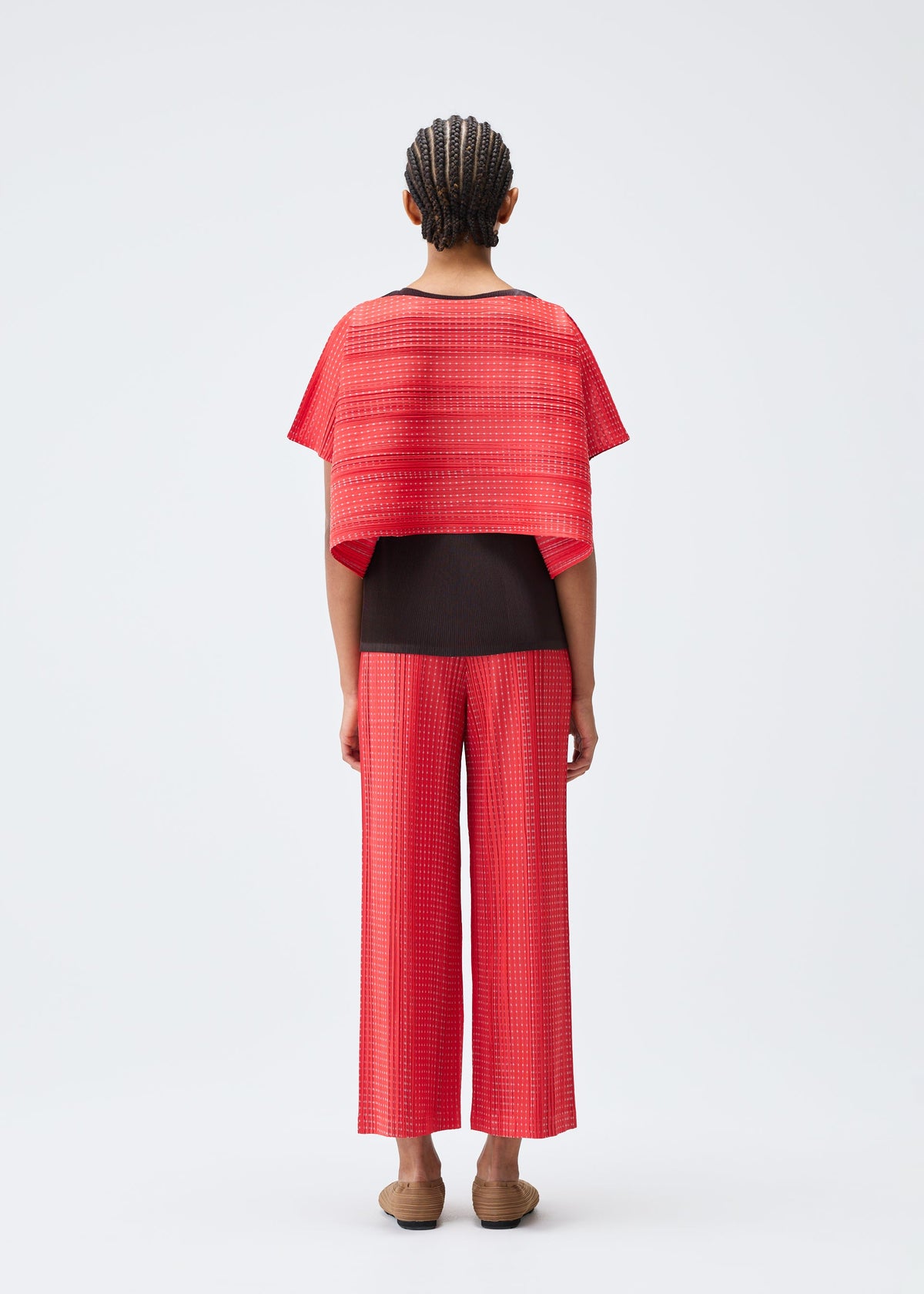 A model wears the PLEATS PLEASE ISSEY MIYAKE COTTON SKIP trousers.