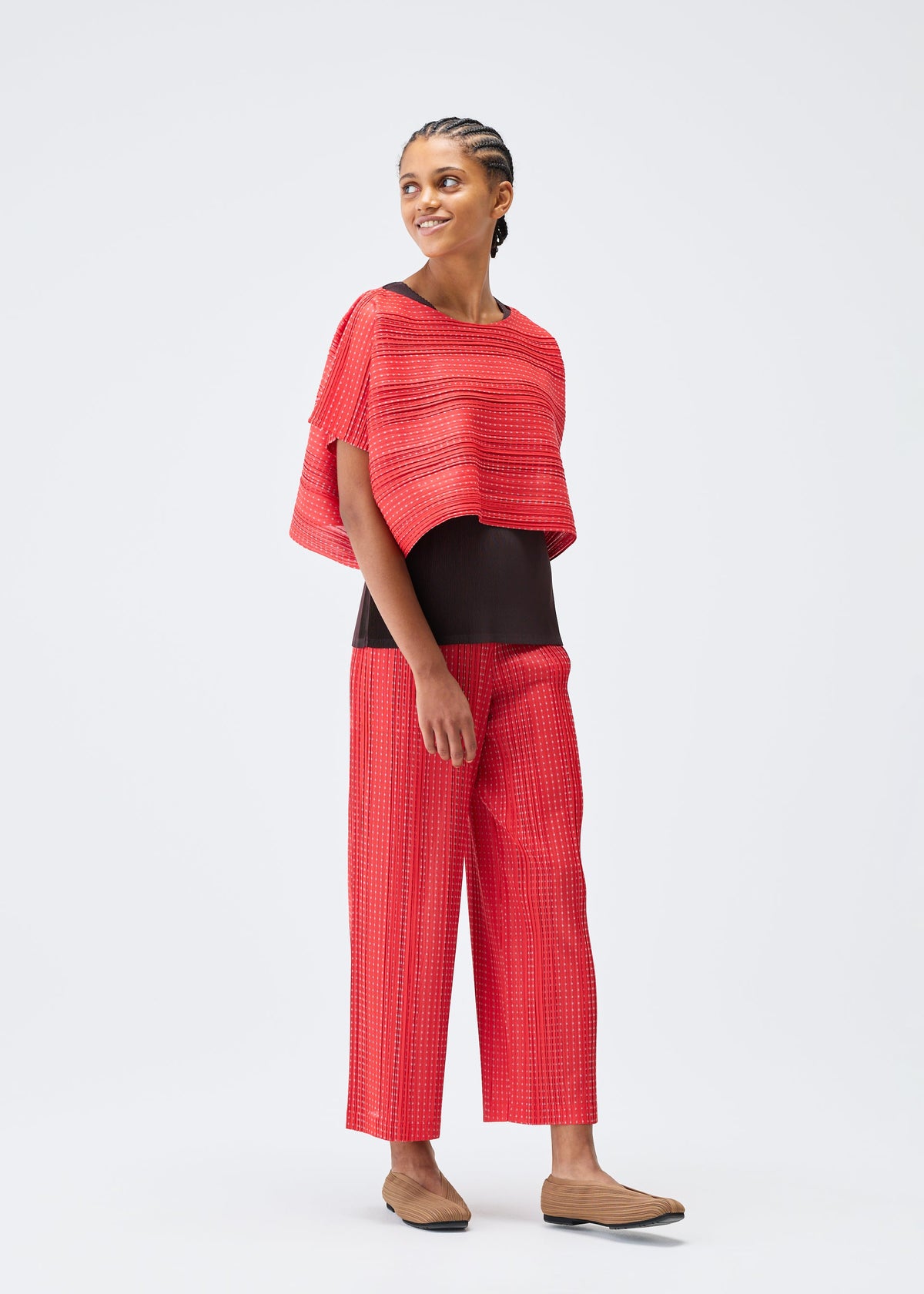 A model wears the PLEATS PLEASE ISSEY MIYAKE COTTON SKIP trousers.