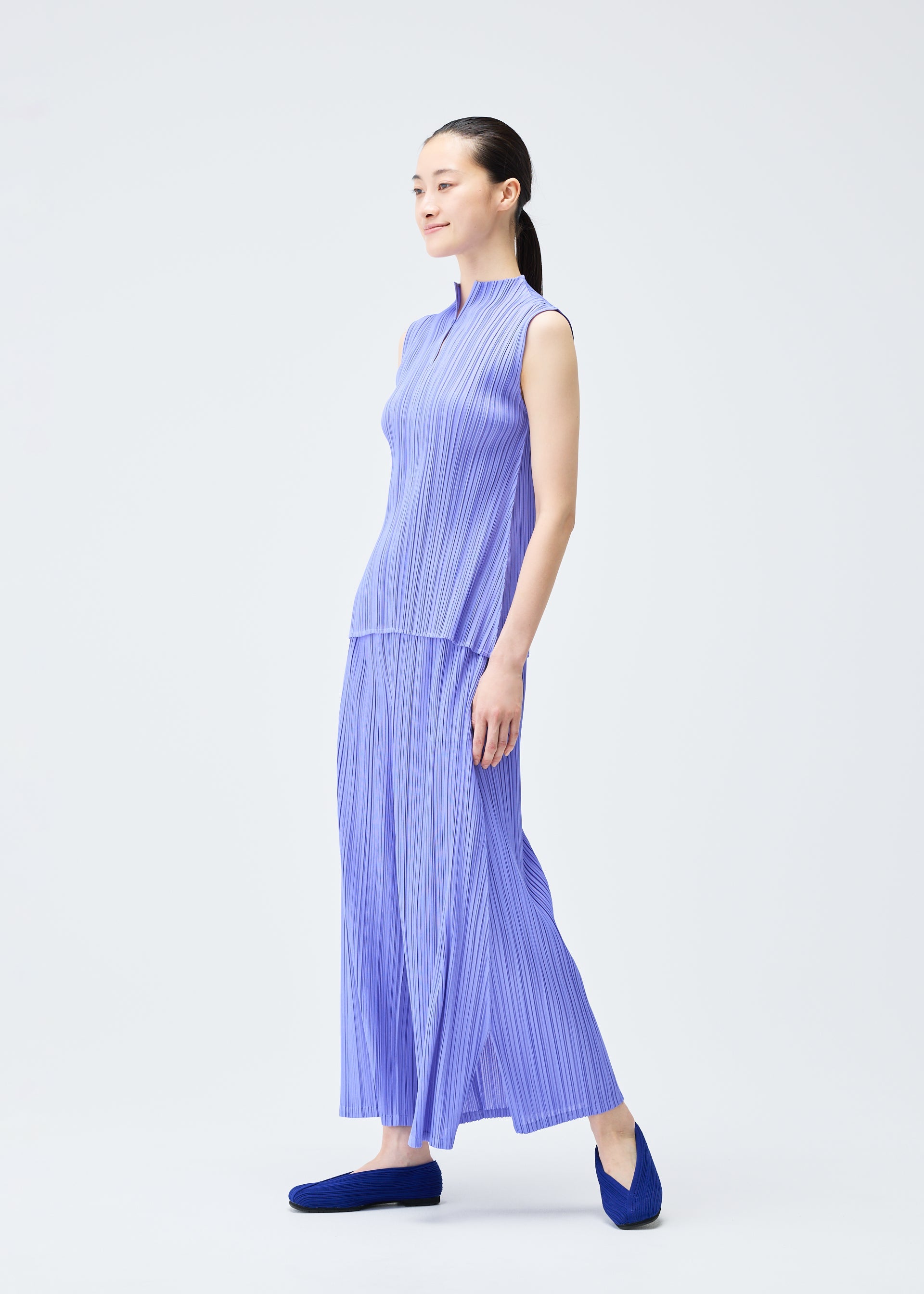 A model wears the PLEATS PLEASE ISSEY MIYAKE MELLOW PLEATS trousers.