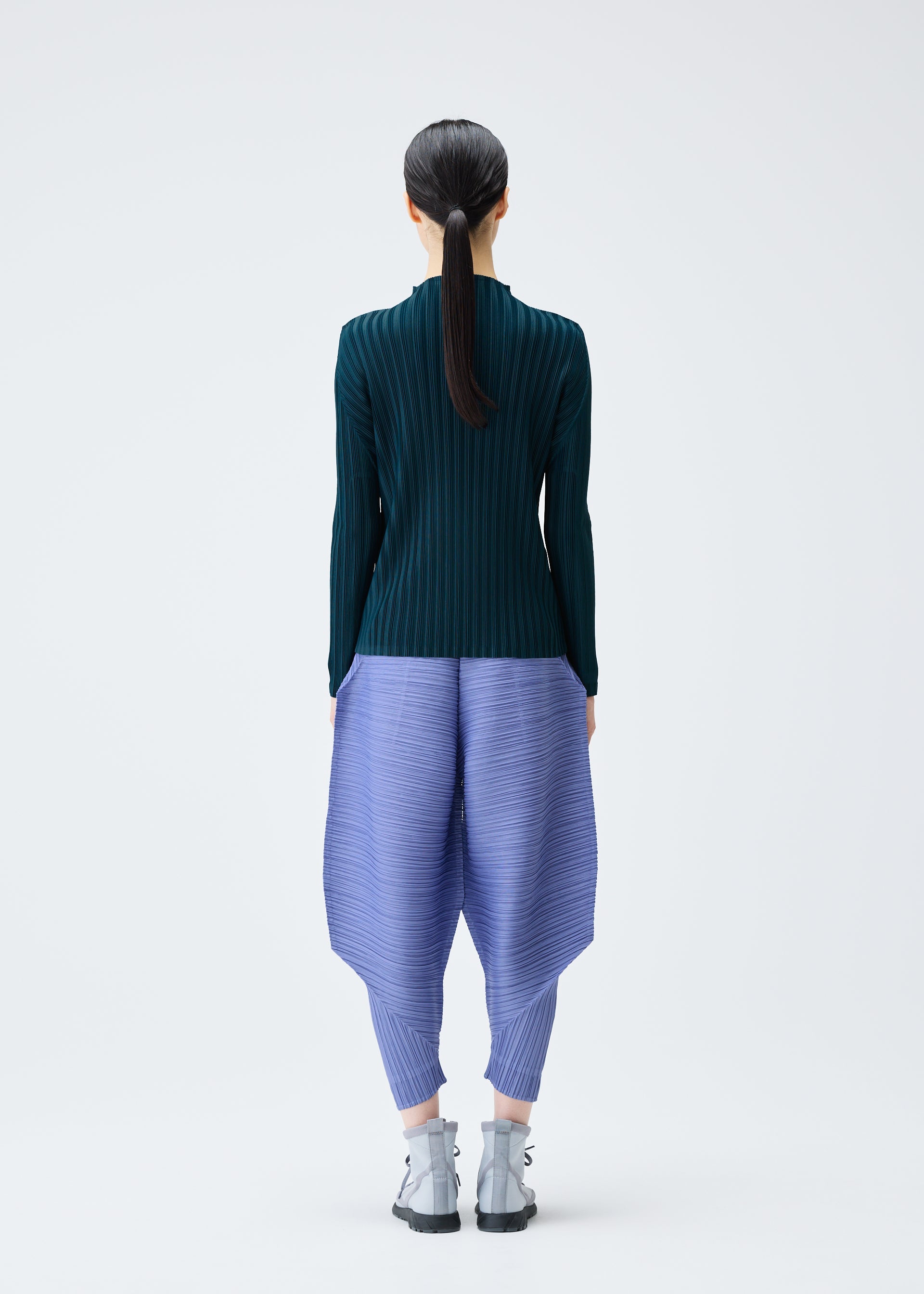 A model wears the PLEATS PLEASE ISSEY MIYAKE THICKER BOUNCE trousers.