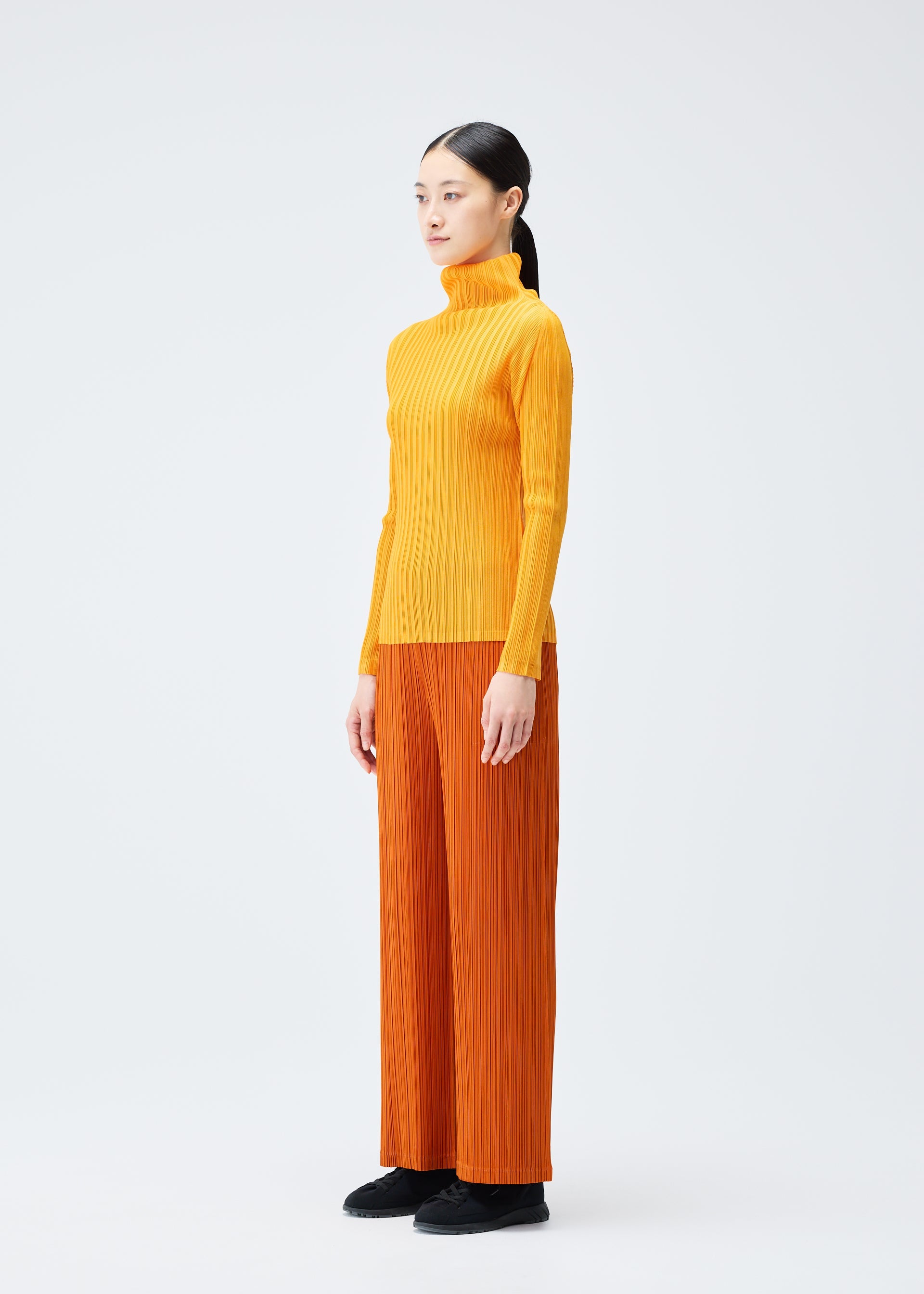 A model wears the PLEATS PLEASE ISSEY MIYAKE LOOP BOTTOMS clothing.