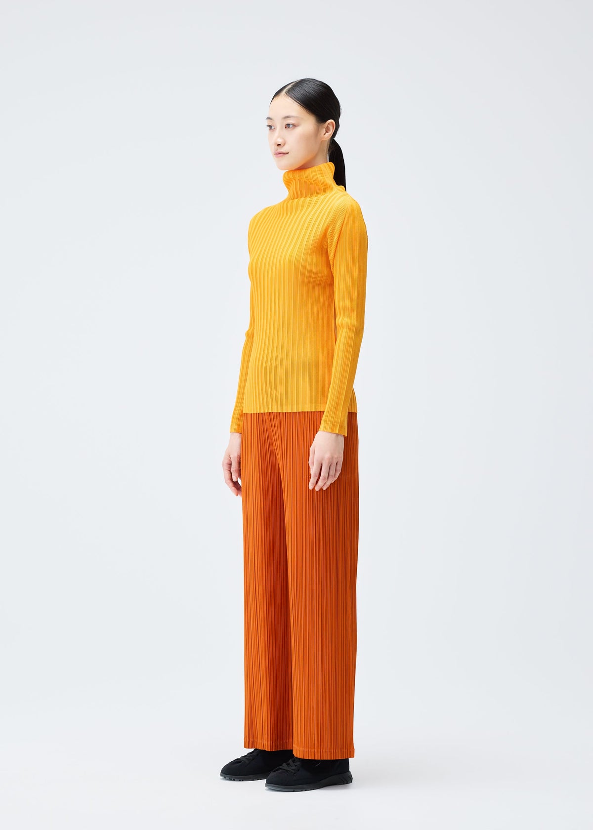 A model wears the PLEATS PLEASE ISSEY MIYAKE LOOP BOTTOMS clothing.