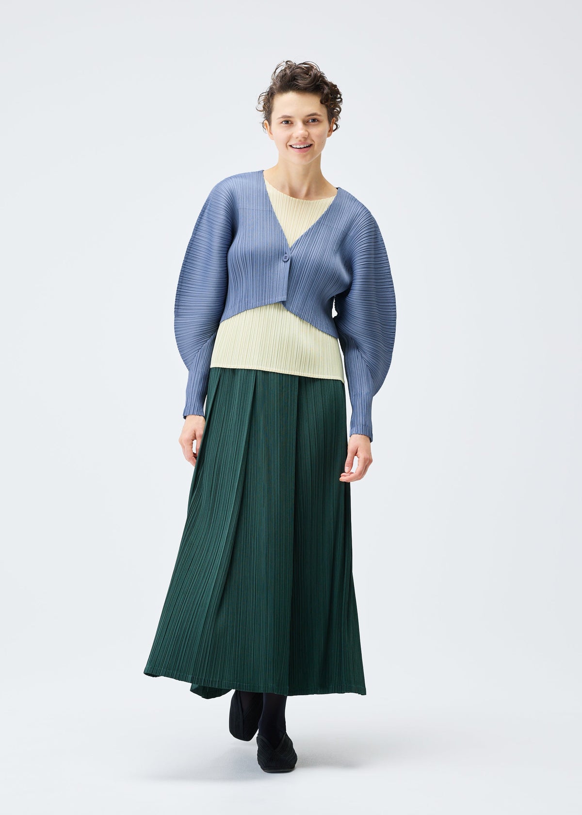 A model wears the PLEATS PLEASE ISSEY MIYAKE MONTHLY COLORS DECEMBER clothing.