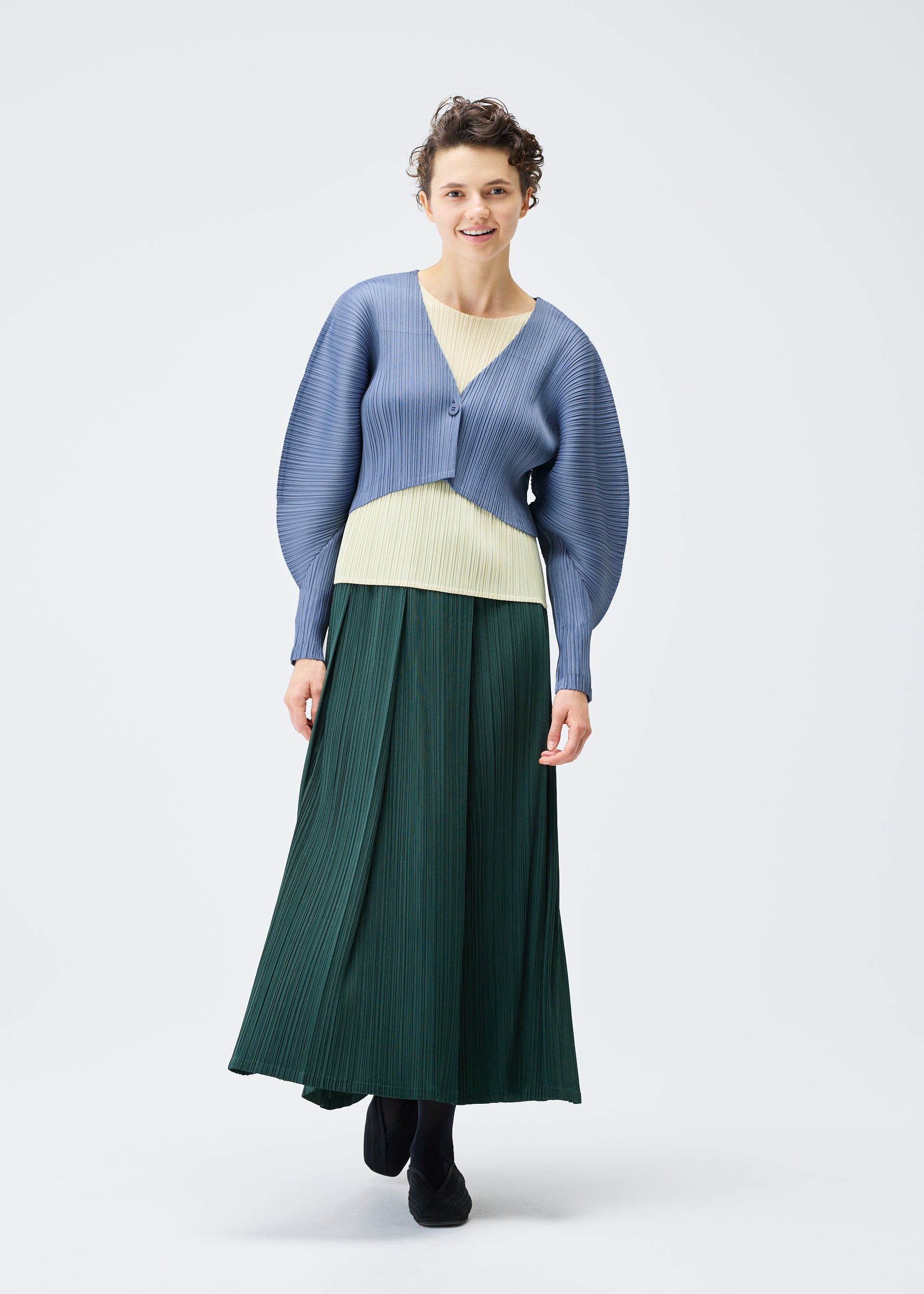 A model wears the PLEATS PLEASE ISSEY MIYAKE MONTHLY COLORS DECEMBER clothing.