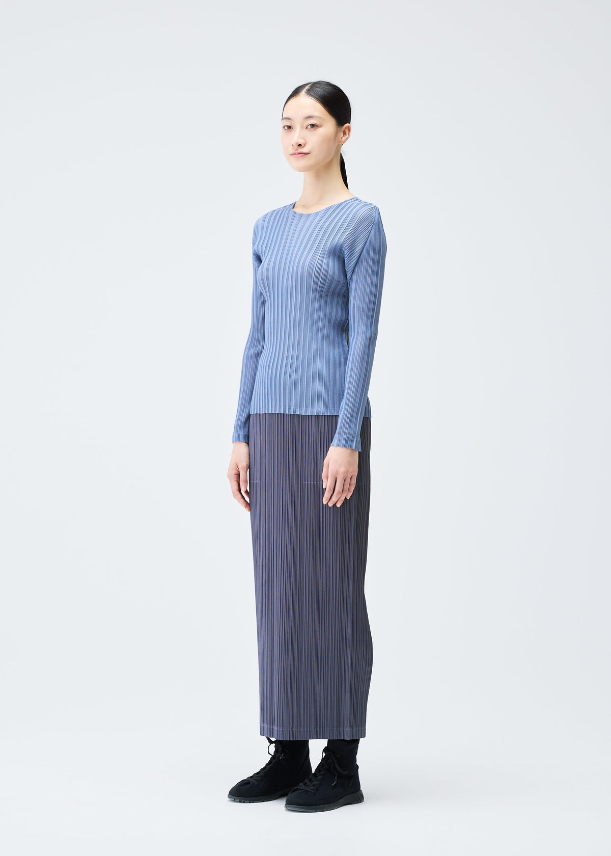 A model wears the PLEATS PLEASE ISSEY MIYAKE LOOP BOTTOMS clothing.