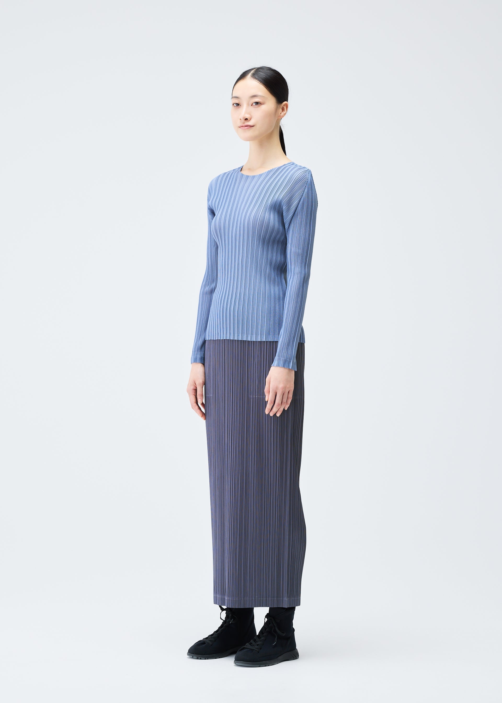 A model wears the PLEATS PLEASE ISSEY MIYAKE LOOP BOTTOMS clothing.