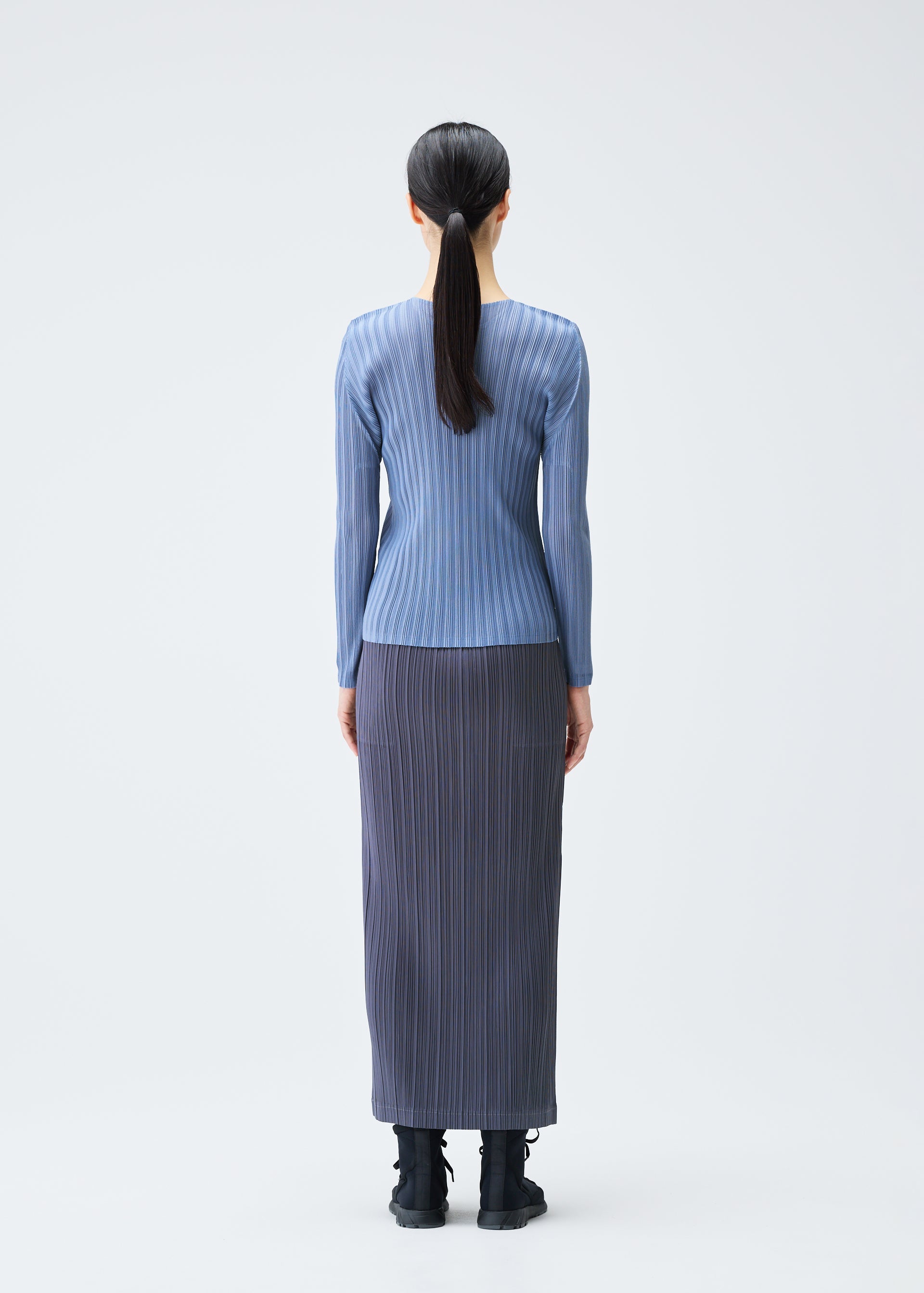 A model wears the PLEATS PLEASE ISSEY MIYAKE LOOP BOTTOMS clothing.