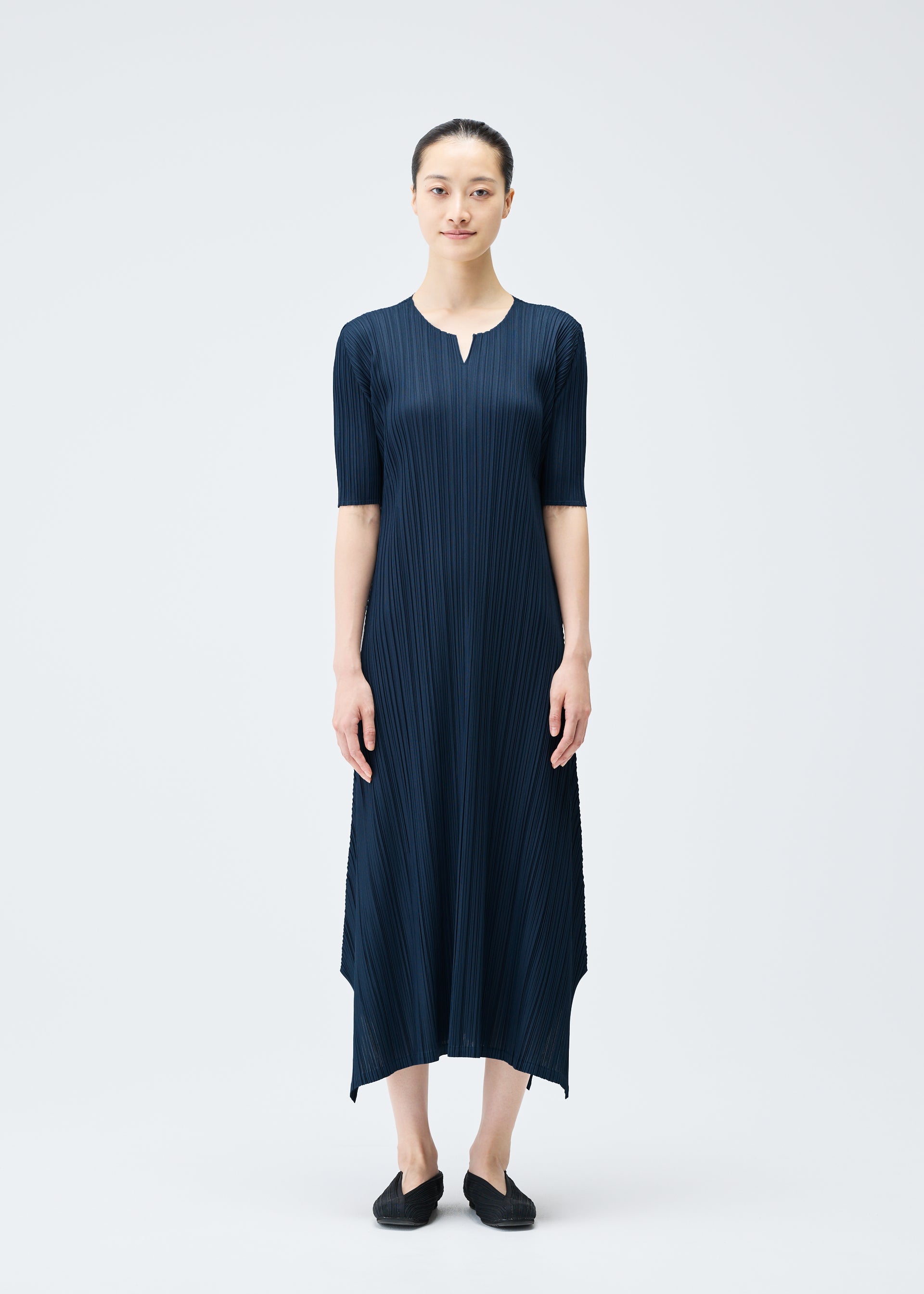 A model wears the PLEATS PLEASE ISSEY MIYAKE MELLOW PLEATS dress.