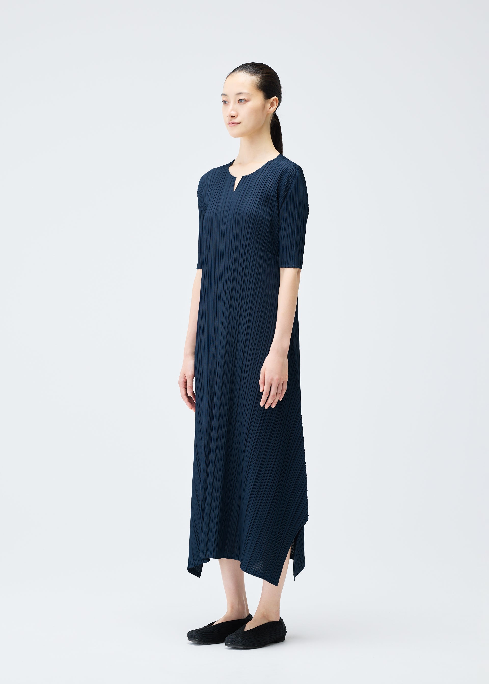 A model wears the PLEATS PLEASE ISSEY MIYAKE MELLOW PLEATS dress.