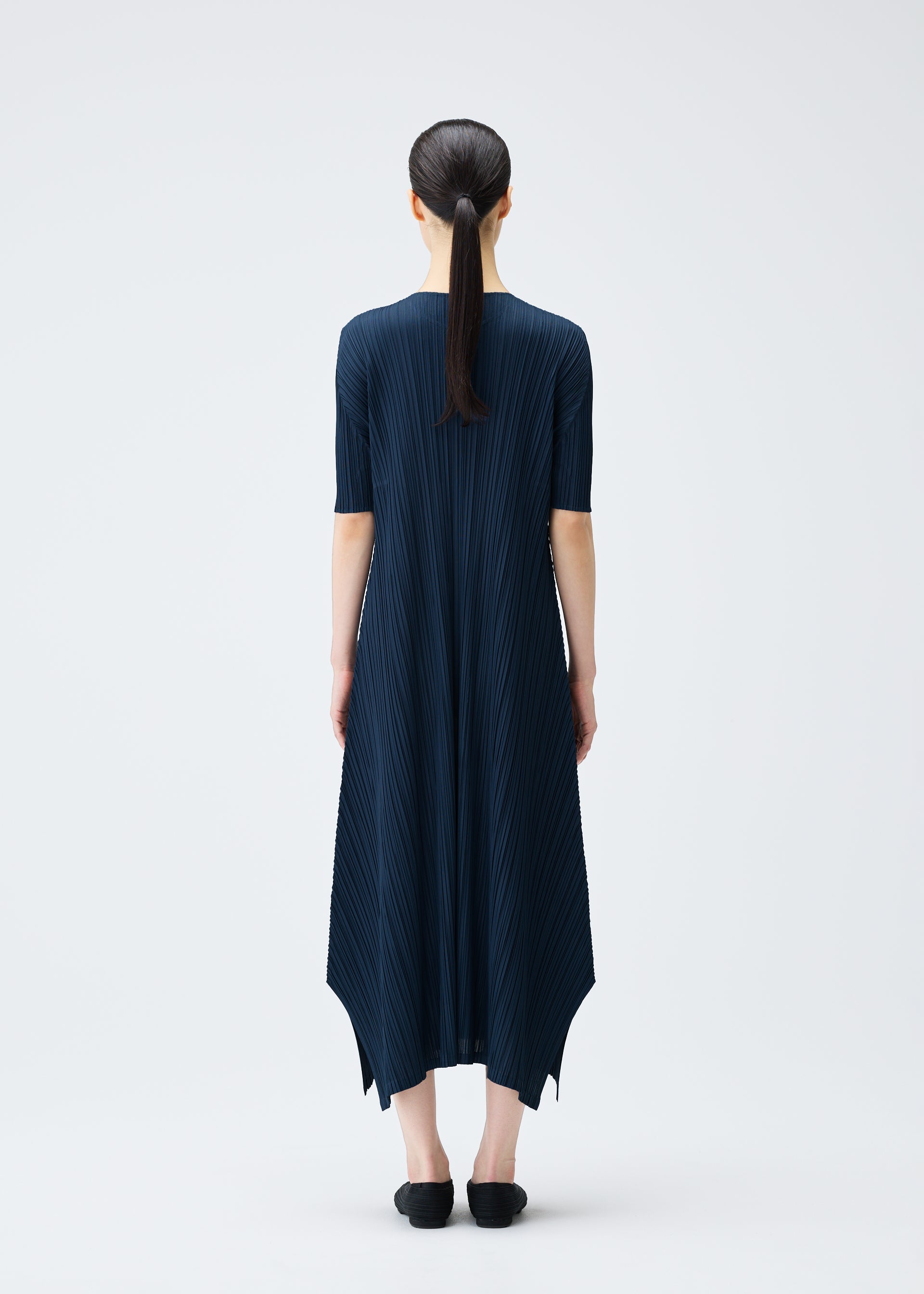 A model wears the PLEATS PLEASE ISSEY MIYAKE MELLOW PLEATS dress.