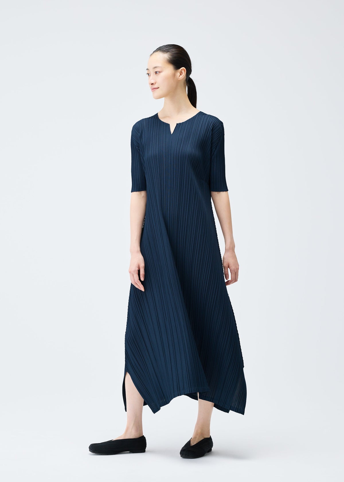 A model wears the PLEATS PLEASE ISSEY MIYAKE MELLOW PLEATS dress.