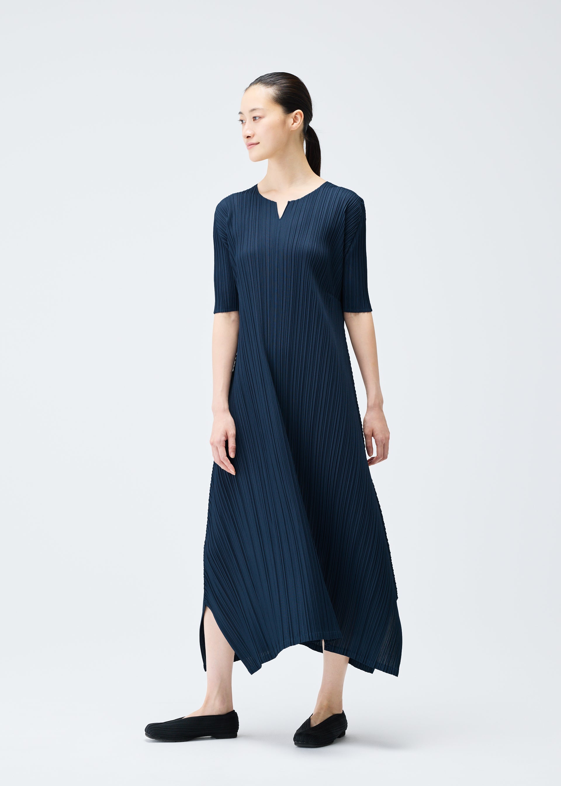 A model wears the PLEATS PLEASE ISSEY MIYAKE MELLOW PLEATS dress.
