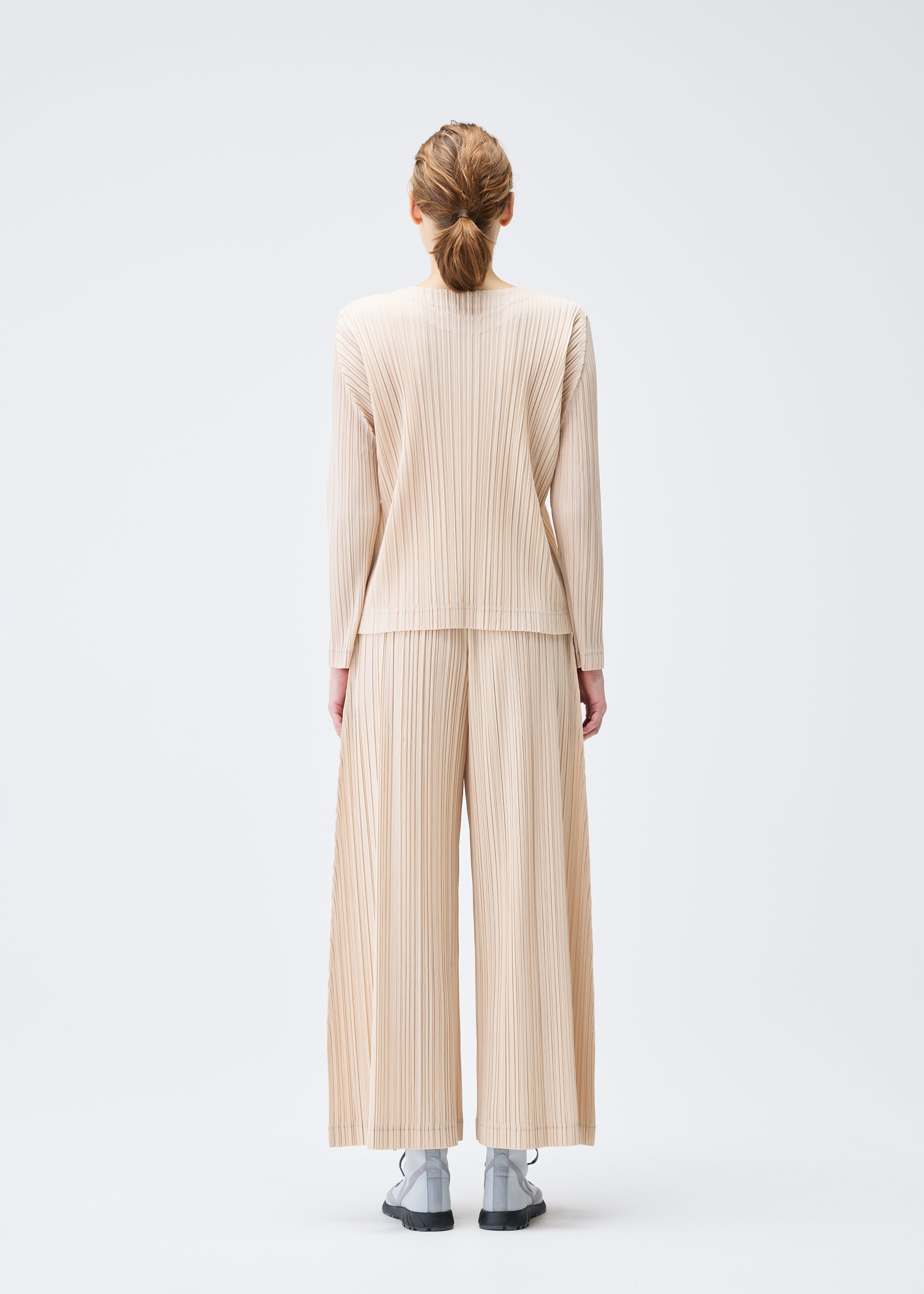 A model wears the PLEATS PLEASE ISSEY MIYAKE WOOL PLEATS top.