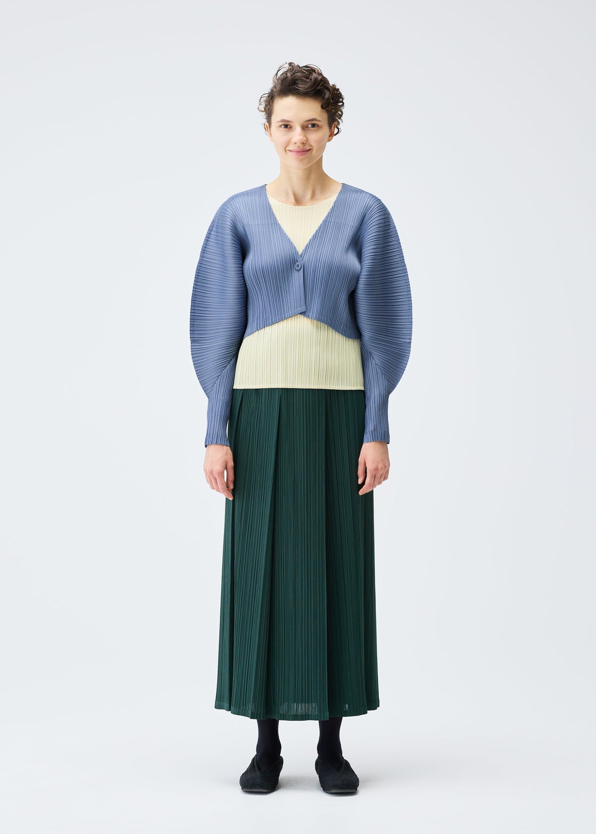 A model wears the PLEATS PLEASE ISSEY MIYAKE MONTHLY COLORS DECEMBER clothing.