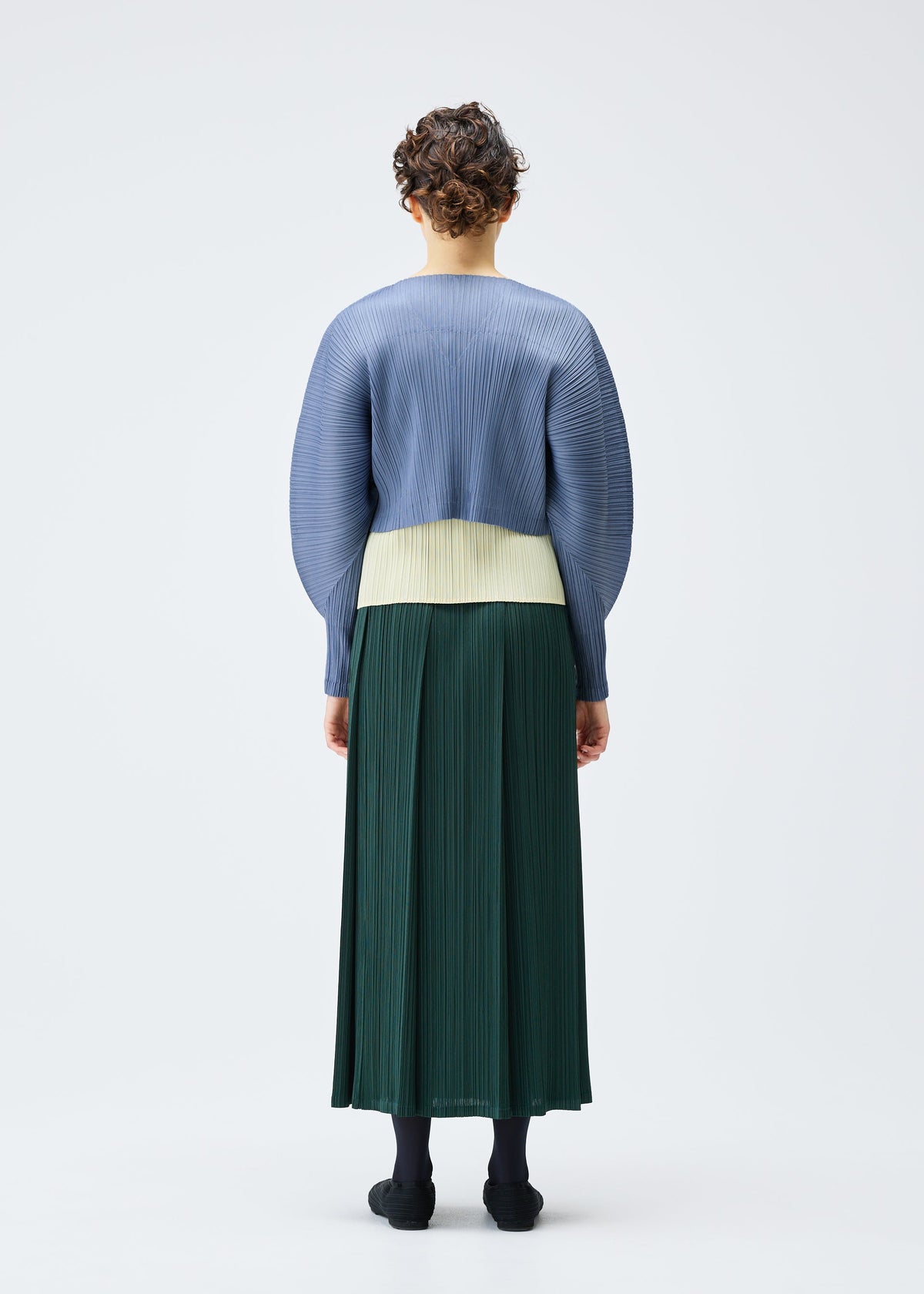 A model wears the PLEATS PLEASE ISSEY MIYAKE MONTHLY COLORS DECEMBER clothing.