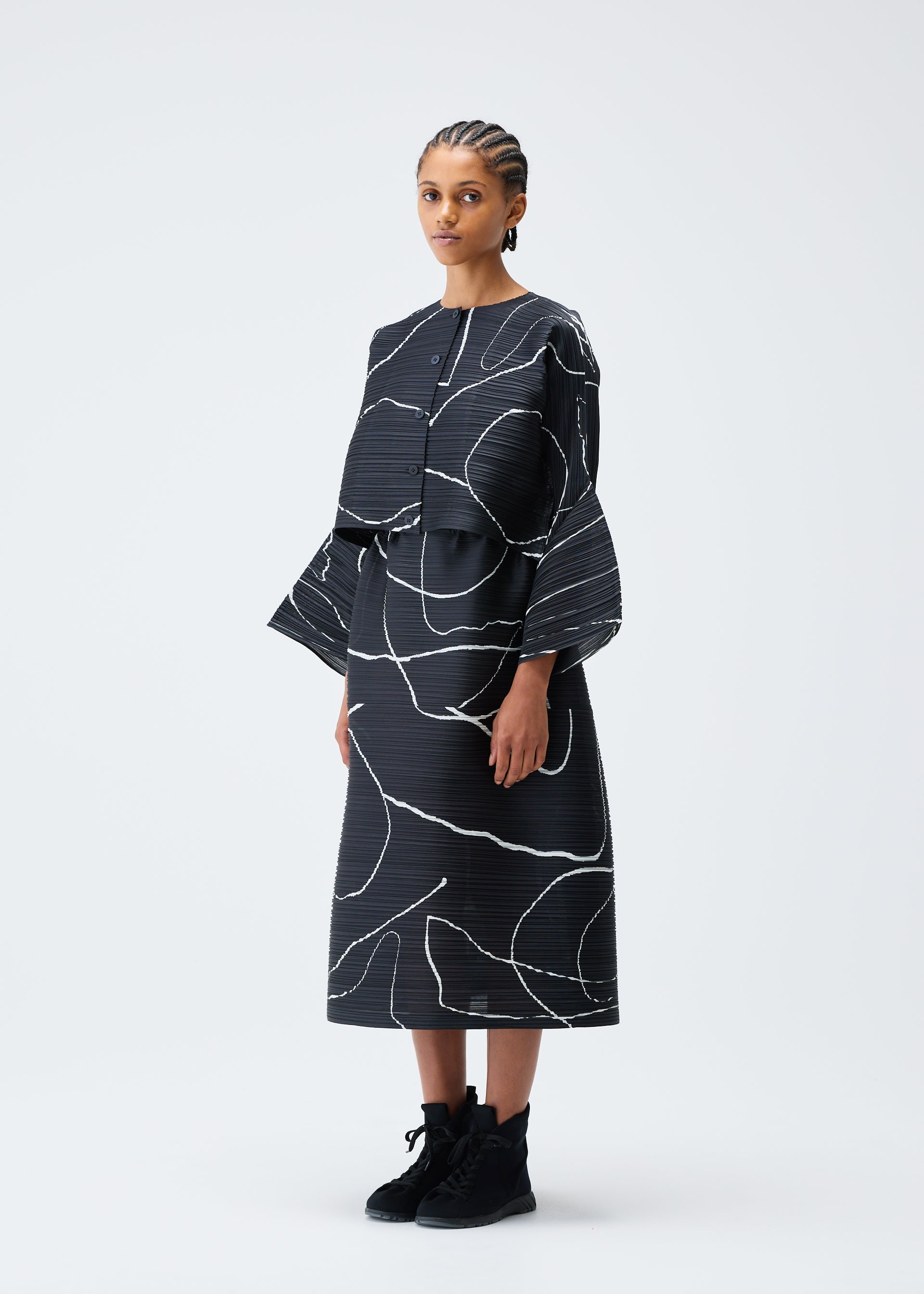 A model wears the PLEATS PLEASE ISSEY MIYAKE PAUSE cardigan.