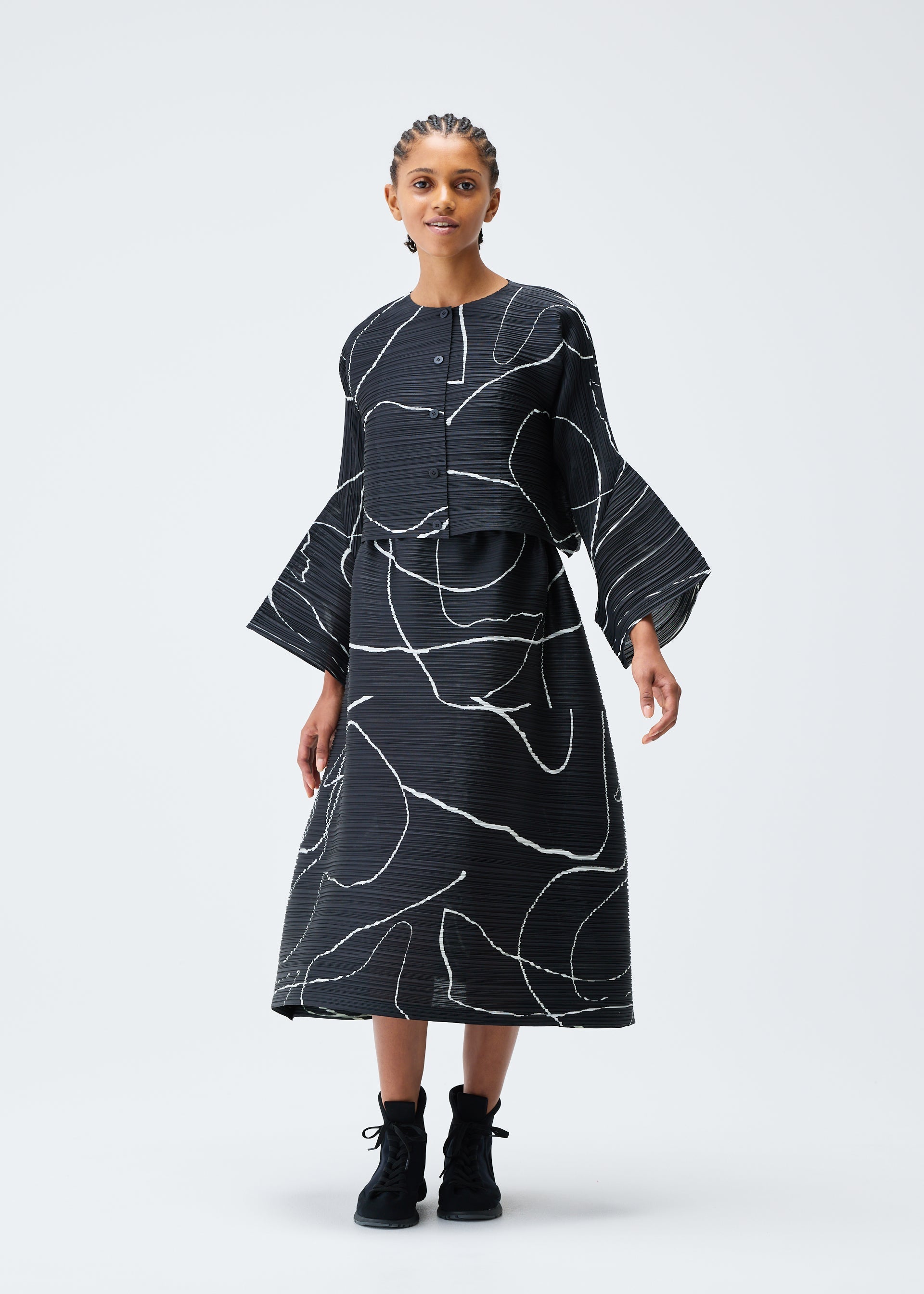 A model wears the PLEATS PLEASE ISSEY MIYAKE PAUSE cardigan.