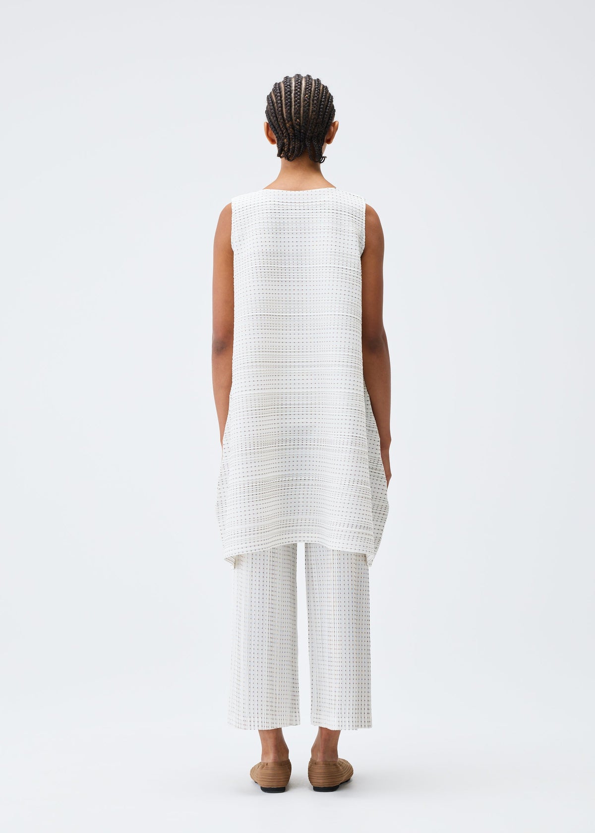 A model wears the PLEATS PLEASE ISSEY MIYAKE COTTON SKIP tunic.