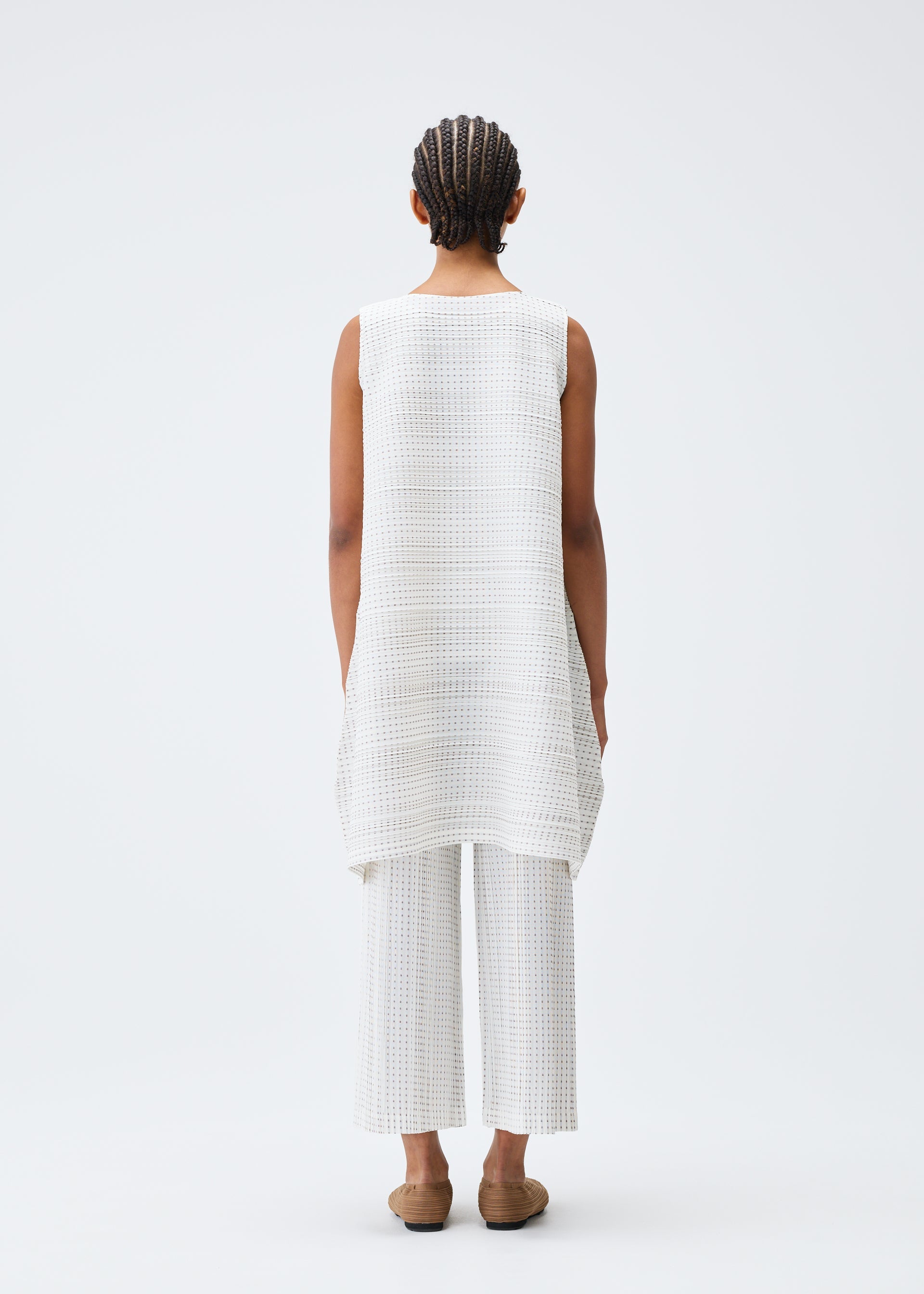 A model wears the PLEATS PLEASE ISSEY MIYAKE COTTON SKIP tunic.