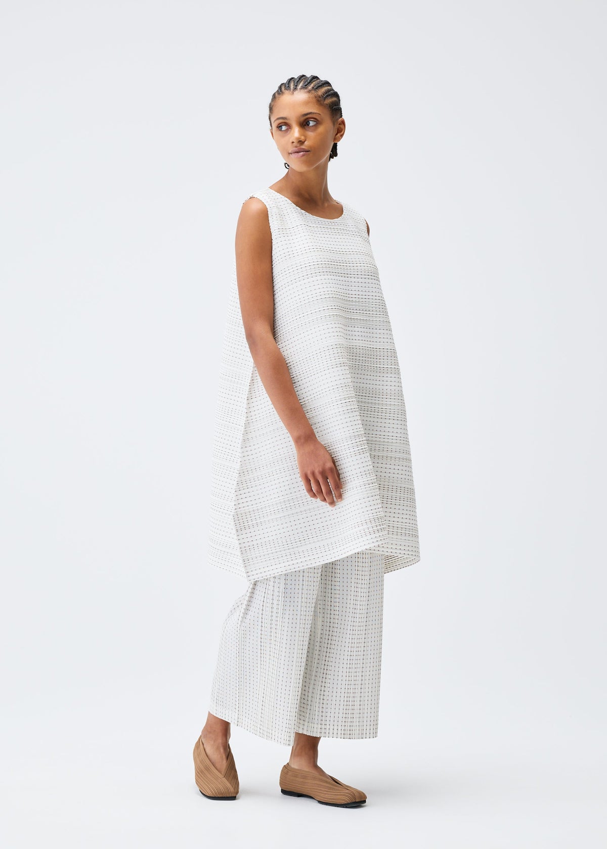 A model wears the PLEATS PLEASE ISSEY MIYAKE COTTON SKIP tunic.