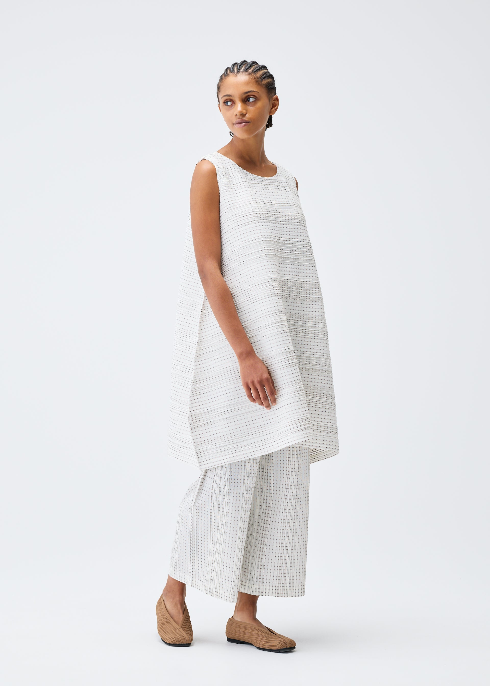 A model wears the PLEATS PLEASE ISSEY MIYAKE COTTON SKIP tunic.