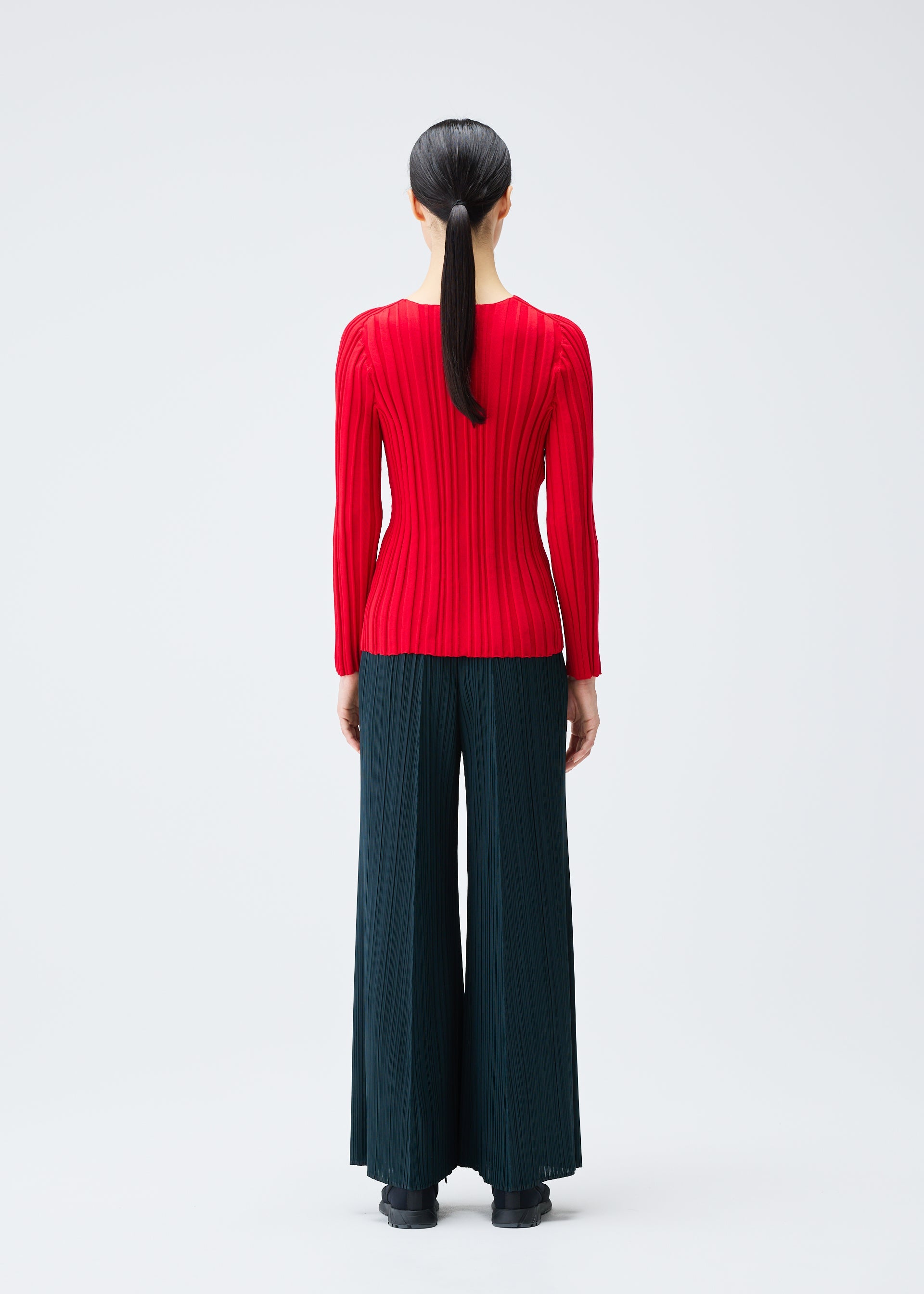 A model wears the PLEATS PLEASE ISSEY MIYAKE RIB KNIT top.