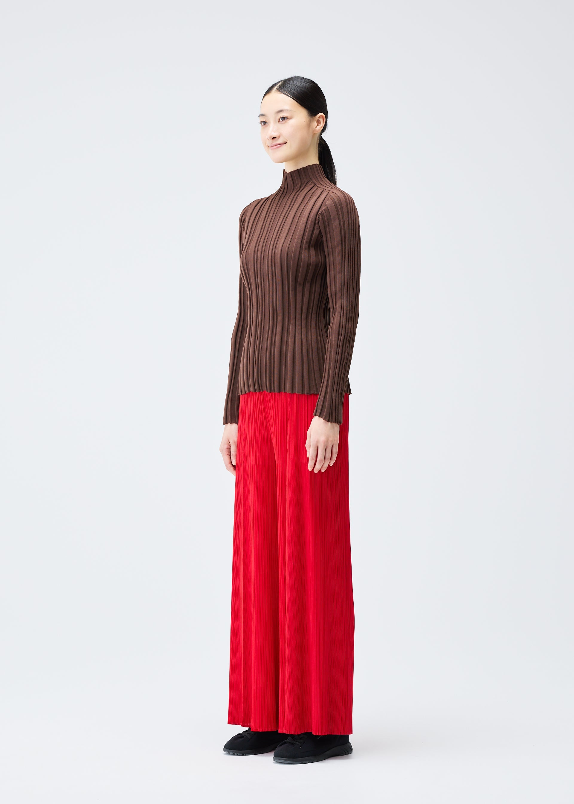 A model wears the PLEATS PLEASE ISSEY MIYAKE RIB KNIT top.