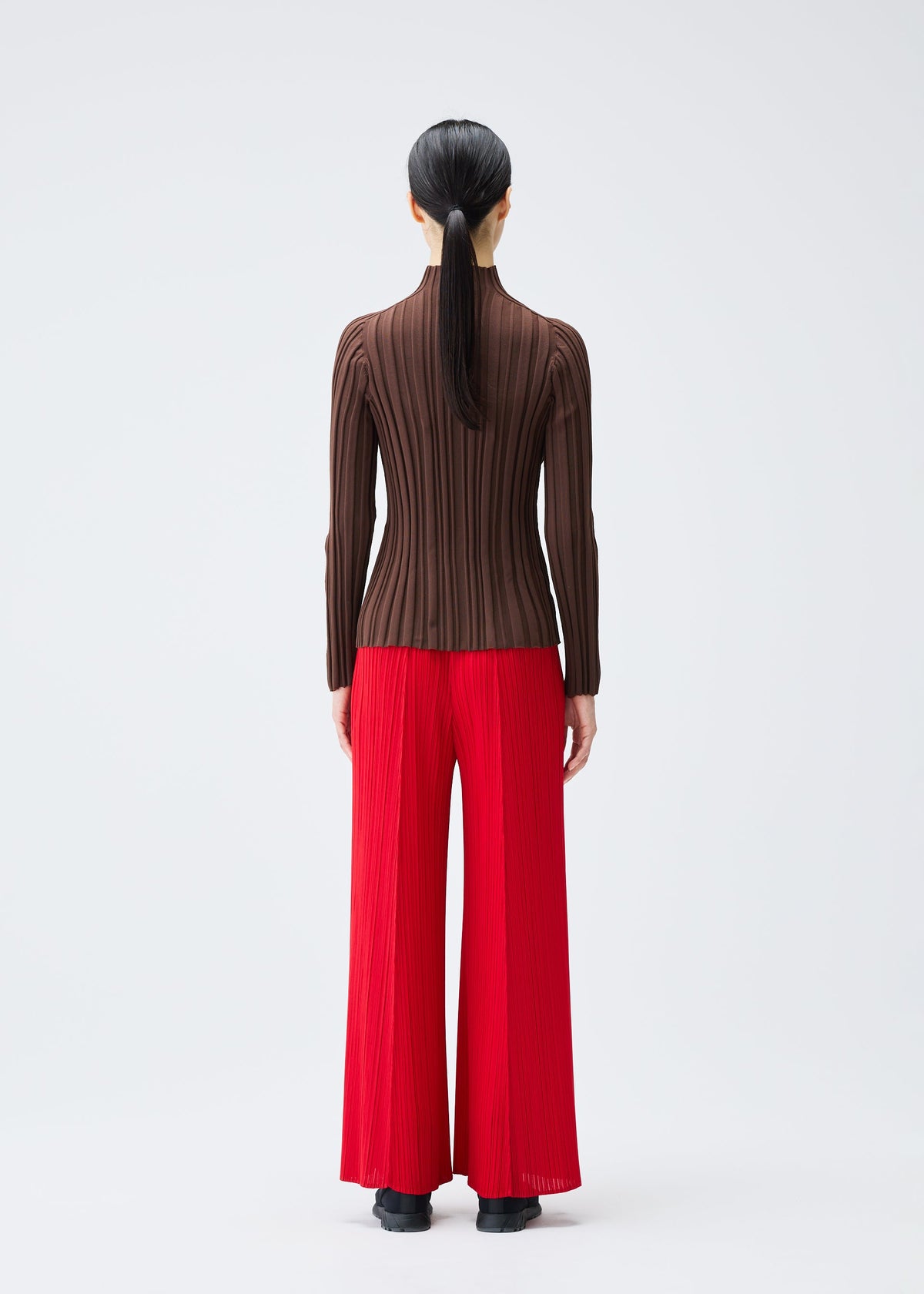 A model wears the PLEATS PLEASE ISSEY MIYAKE RIB KNIT top.