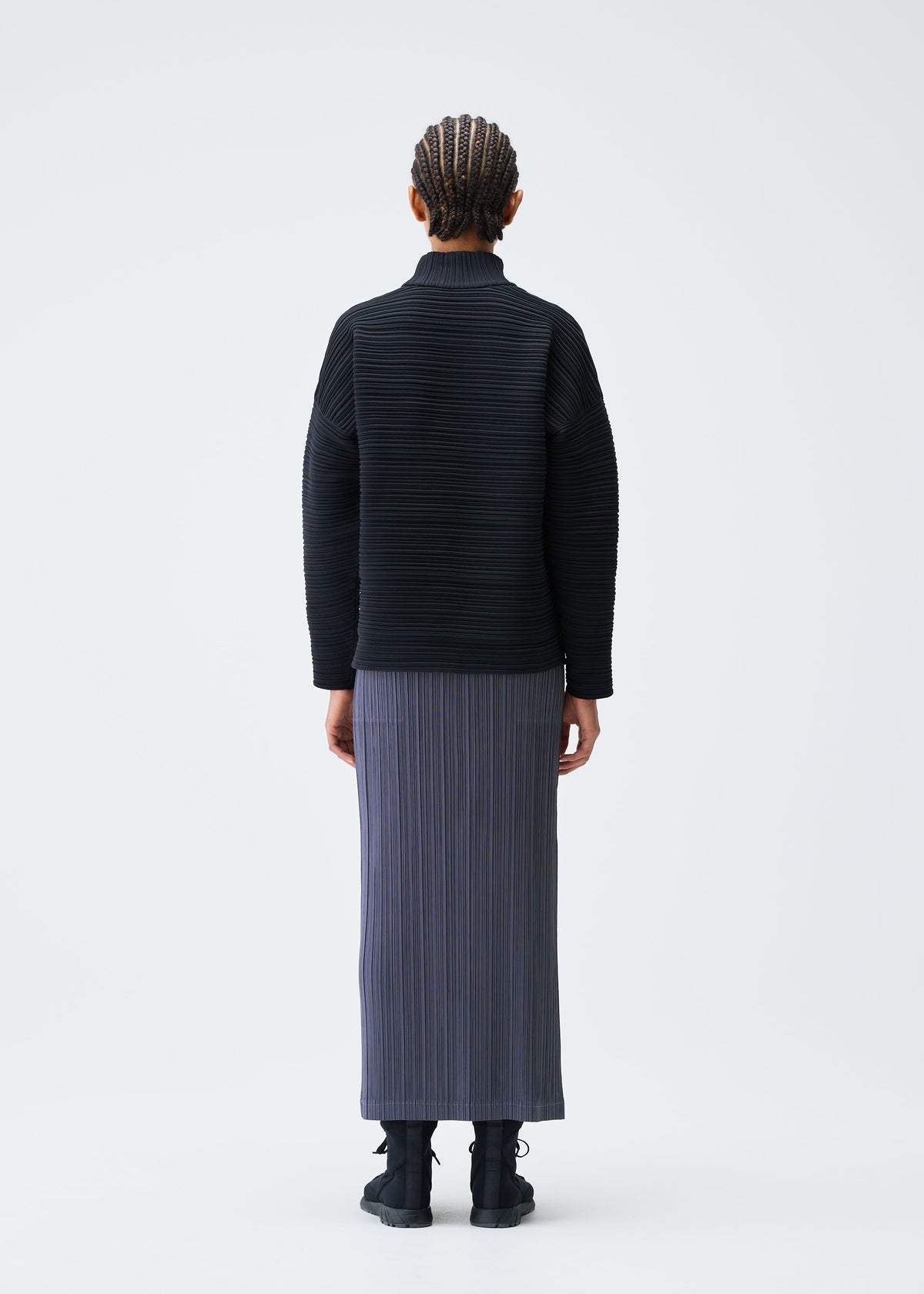 A model wears the PLEATS PLEASE ISSEY MIYAKE CREPE KNIT clothing.