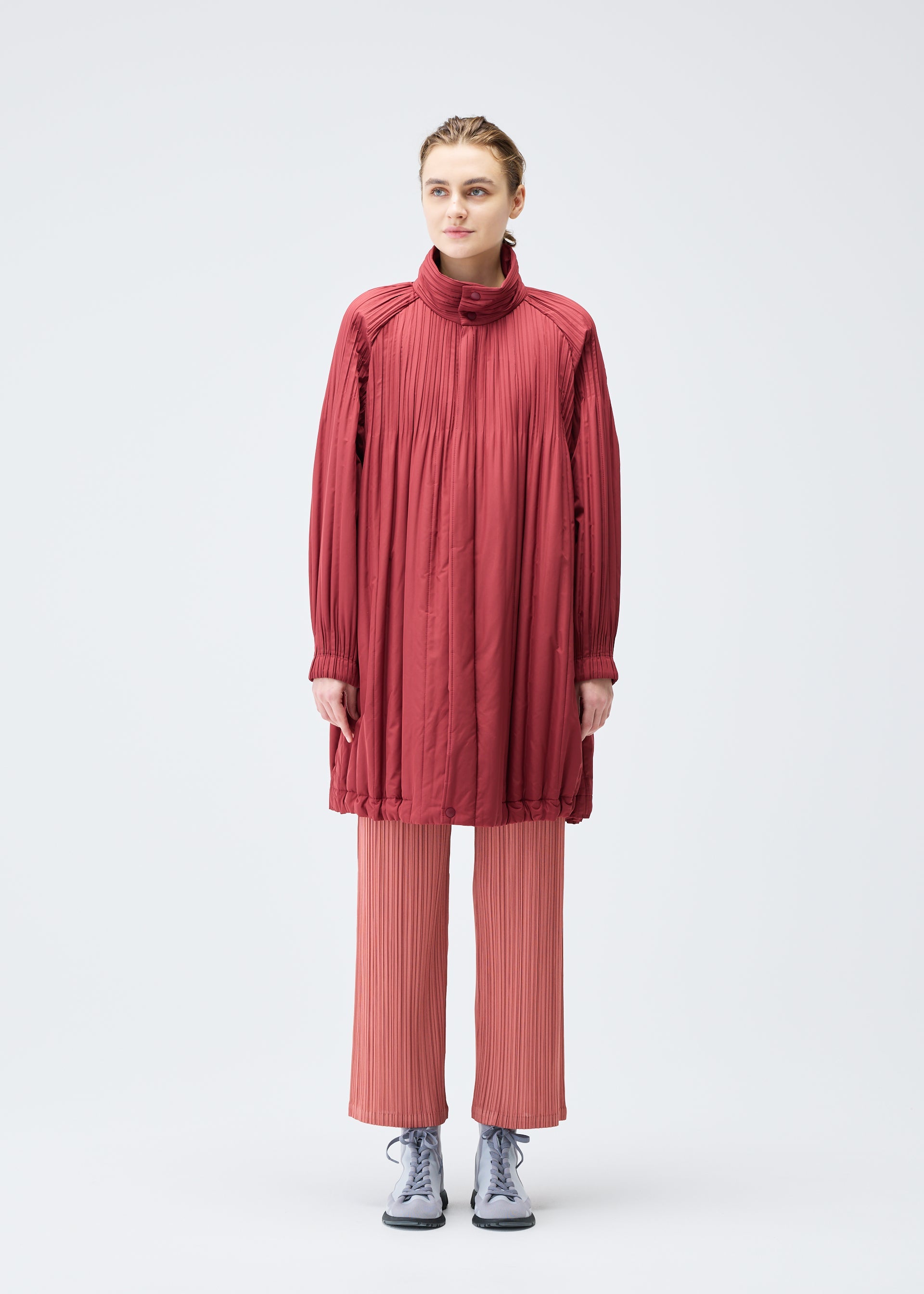 A model wears the PLEATS PLEASE ISSEY MIYAKE PADDED PLEATS COAT coat.