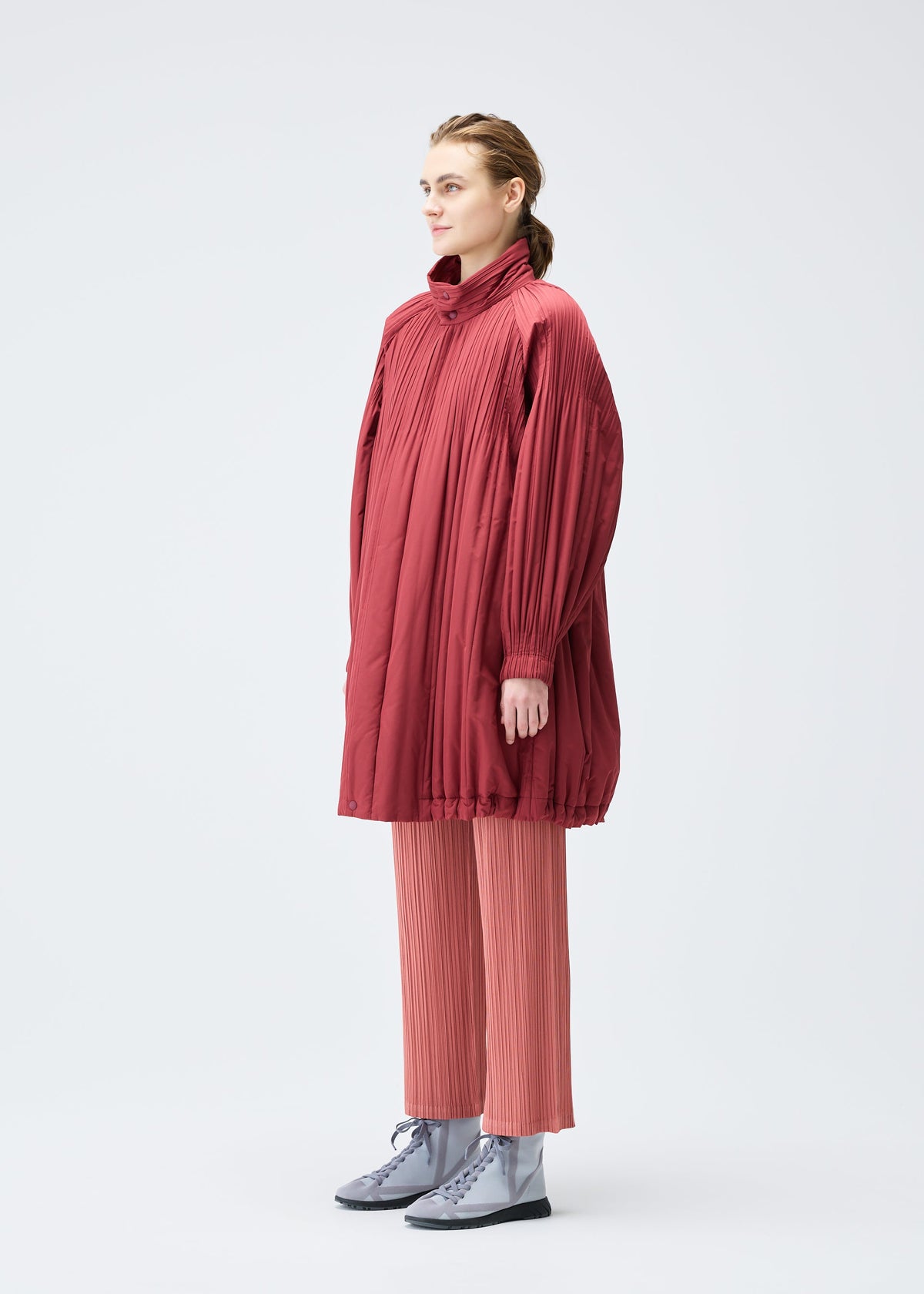A model wears the PLEATS PLEASE ISSEY MIYAKE PADDED PLEATS COAT coat.