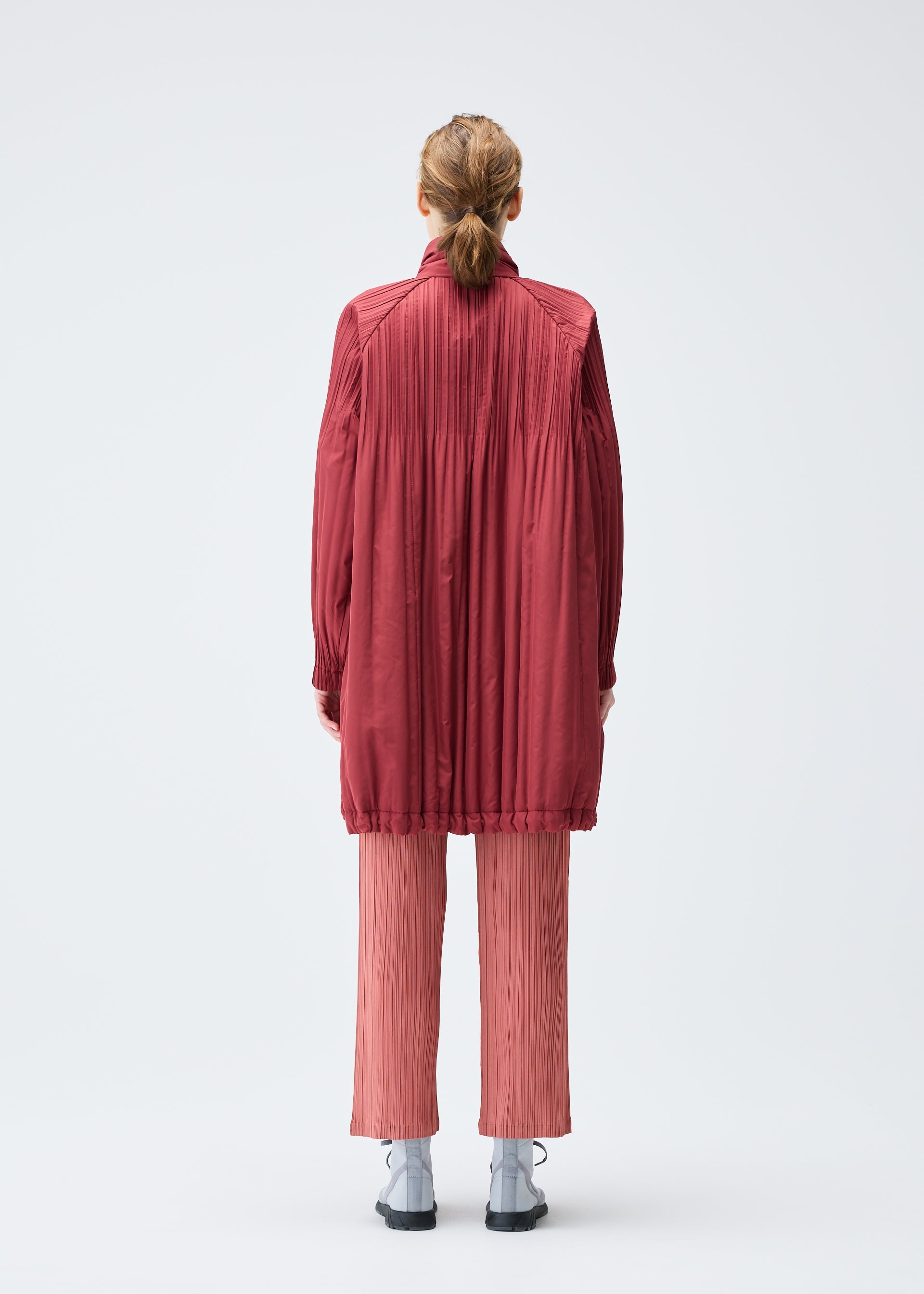 A model wears the PLEATS PLEASE ISSEY MIYAKE PADDED PLEATS COAT coat.