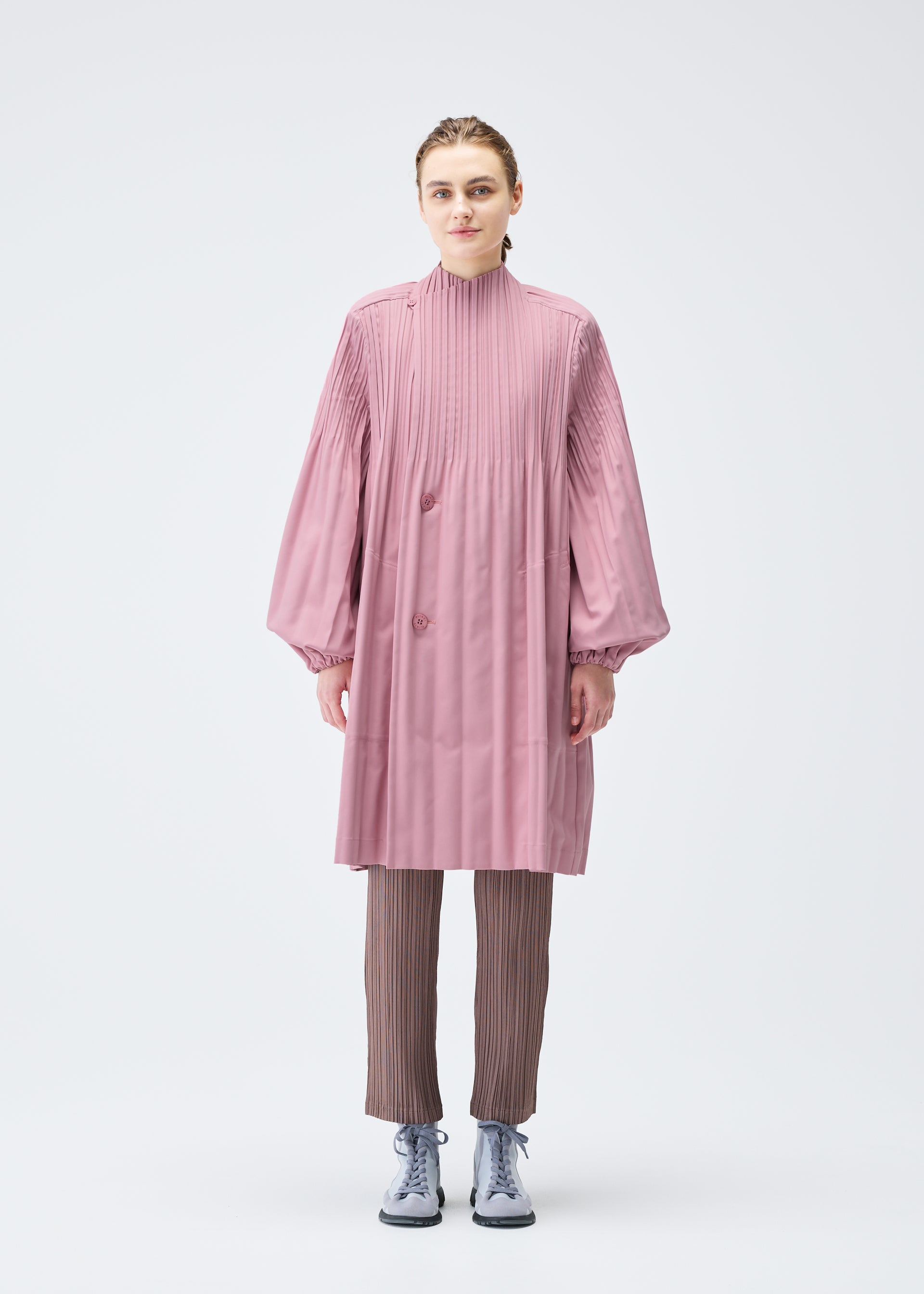 A model wears the PLEATS PLEASE ISSEY MIYAKE SMOOTH COAT coat.