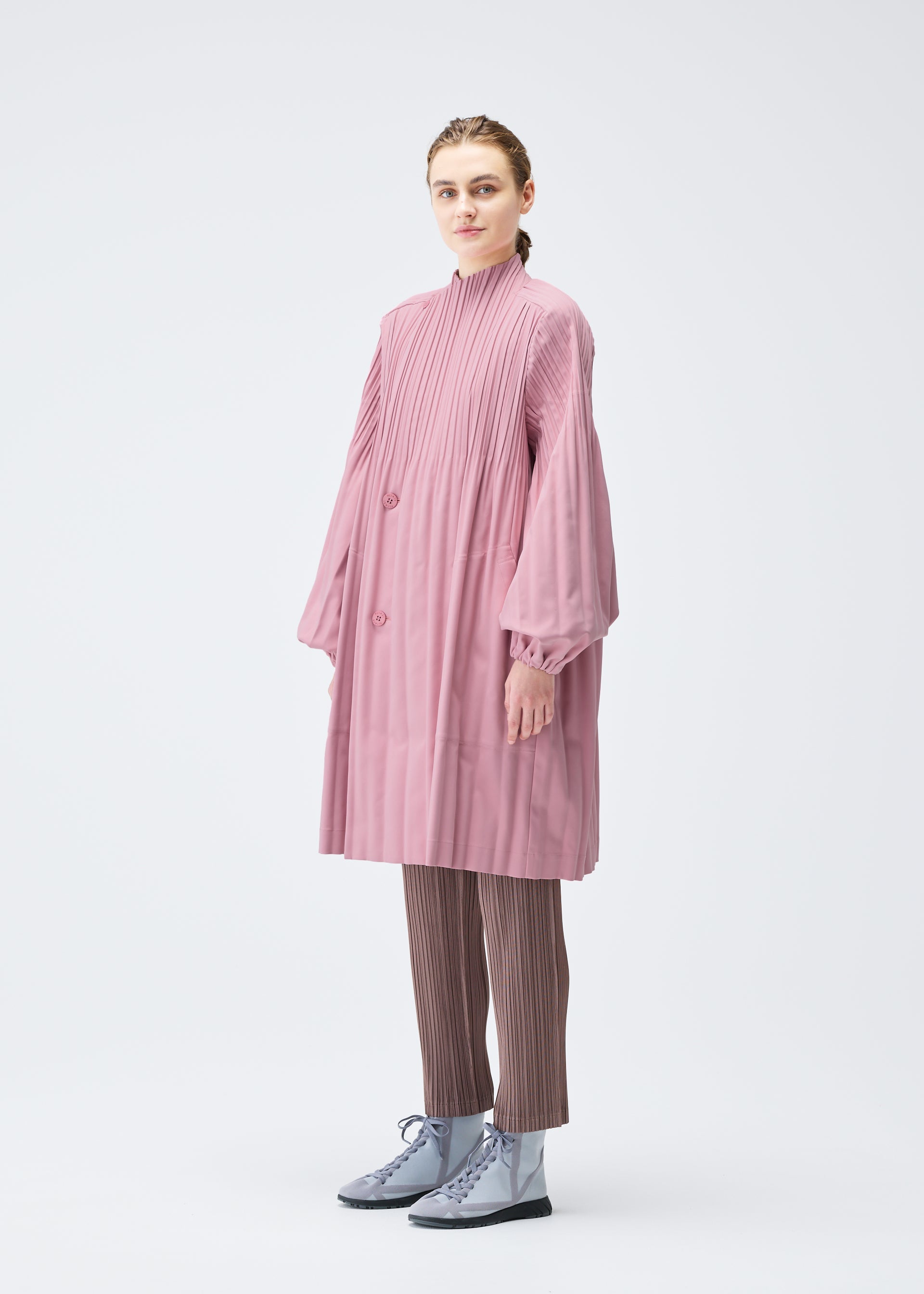 A model wears the PLEATS PLEASE ISSEY MIYAKE SMOOTH COAT coat.