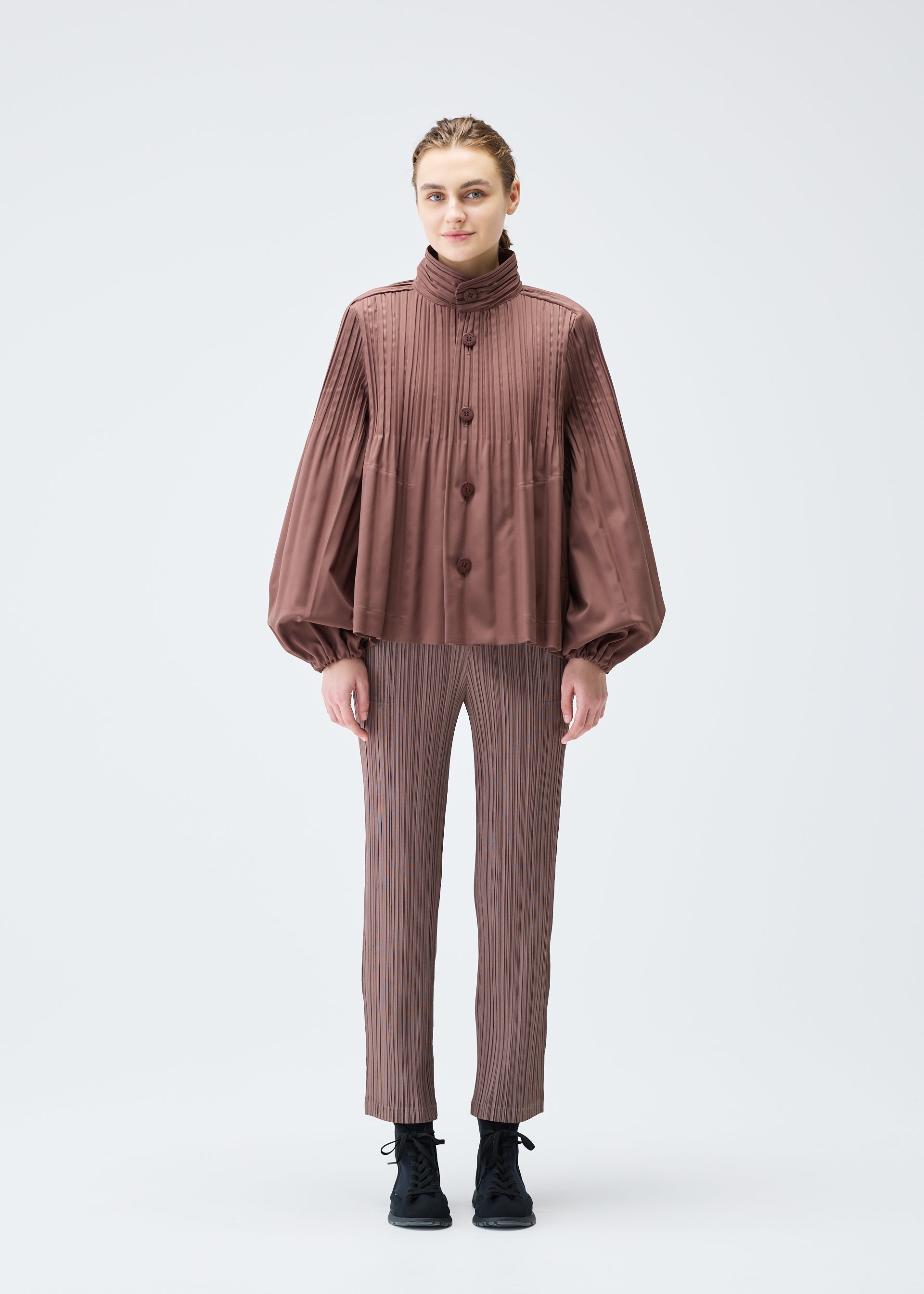 A model wears the PLEATS PLEASE ISSEY MIYAKE SMOOTH COAT jacket.