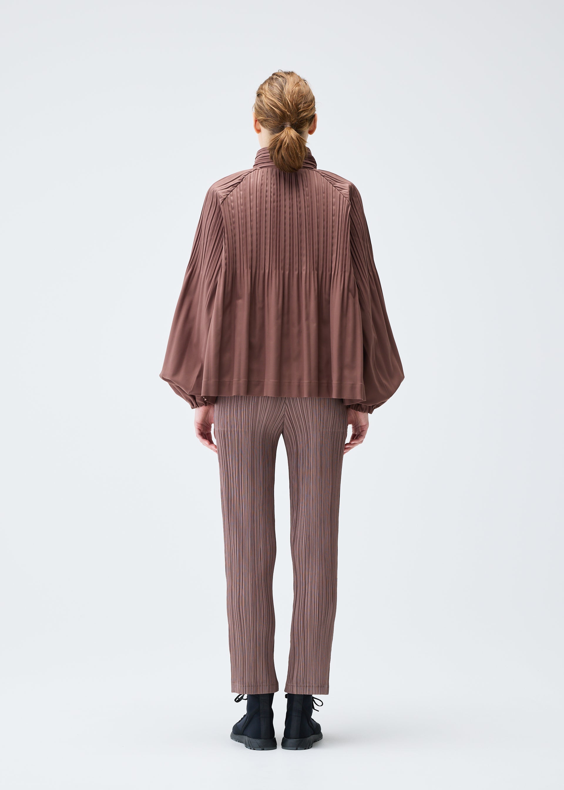 A model wears the PLEATS PLEASE ISSEY MIYAKE SMOOTH COAT jacket.