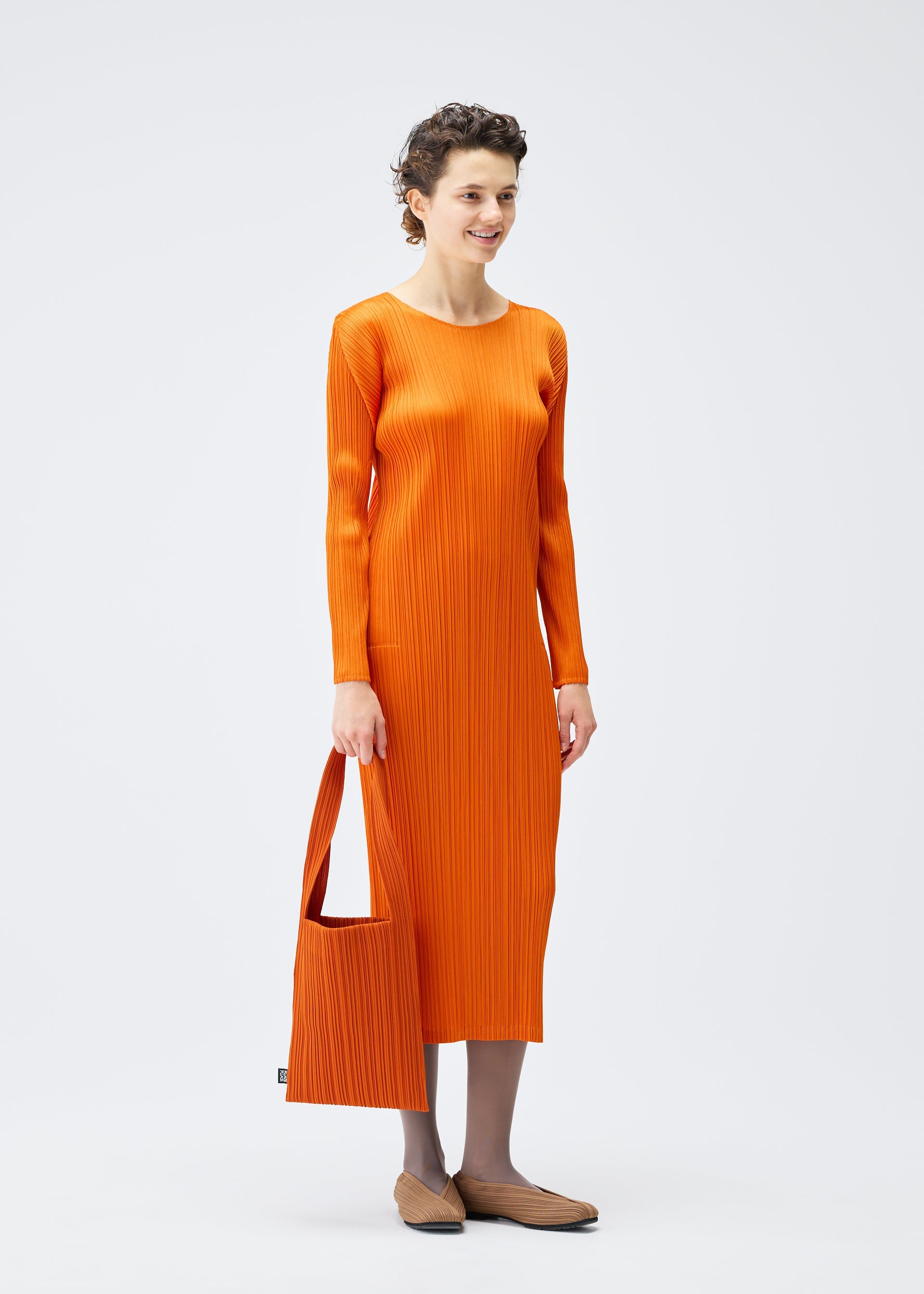 A model wears the PLEATS PLEASE ISSEY MIYAKE CREPE KNIT BAG bags.