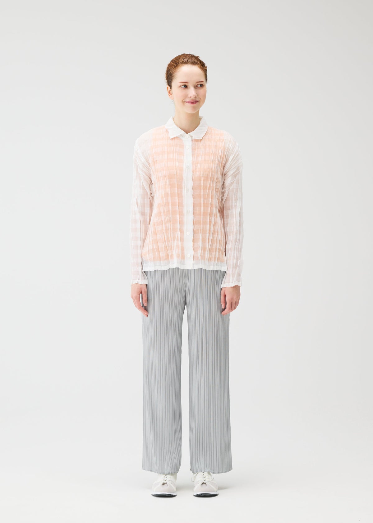 A model wears the PLEATS PLEASE ISSEY MIYAKE TWISTED BORDER SHIRT shirt.
