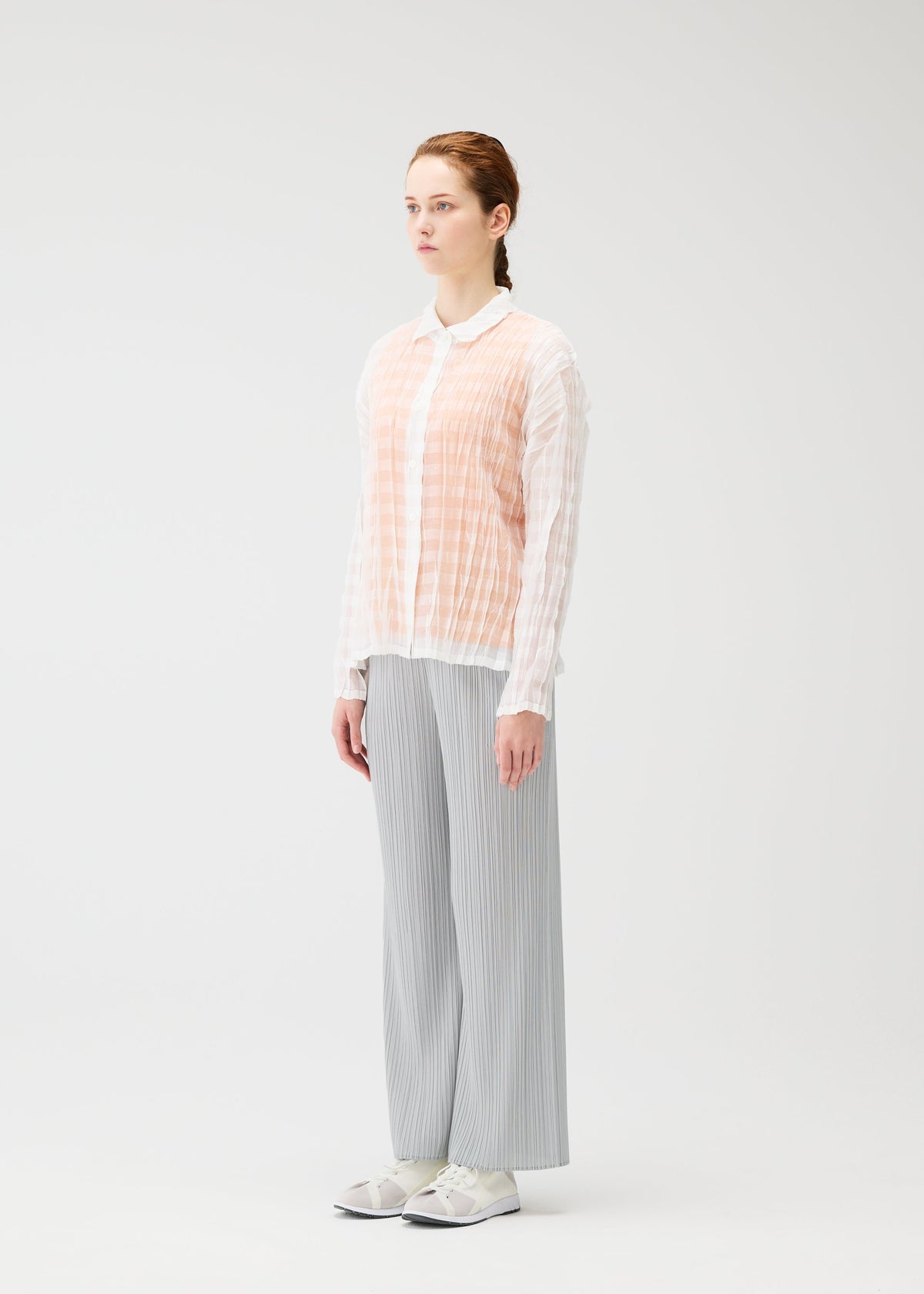 A model wears the PLEATS PLEASE ISSEY MIYAKE TWISTED BORDER SHIRT shirt.