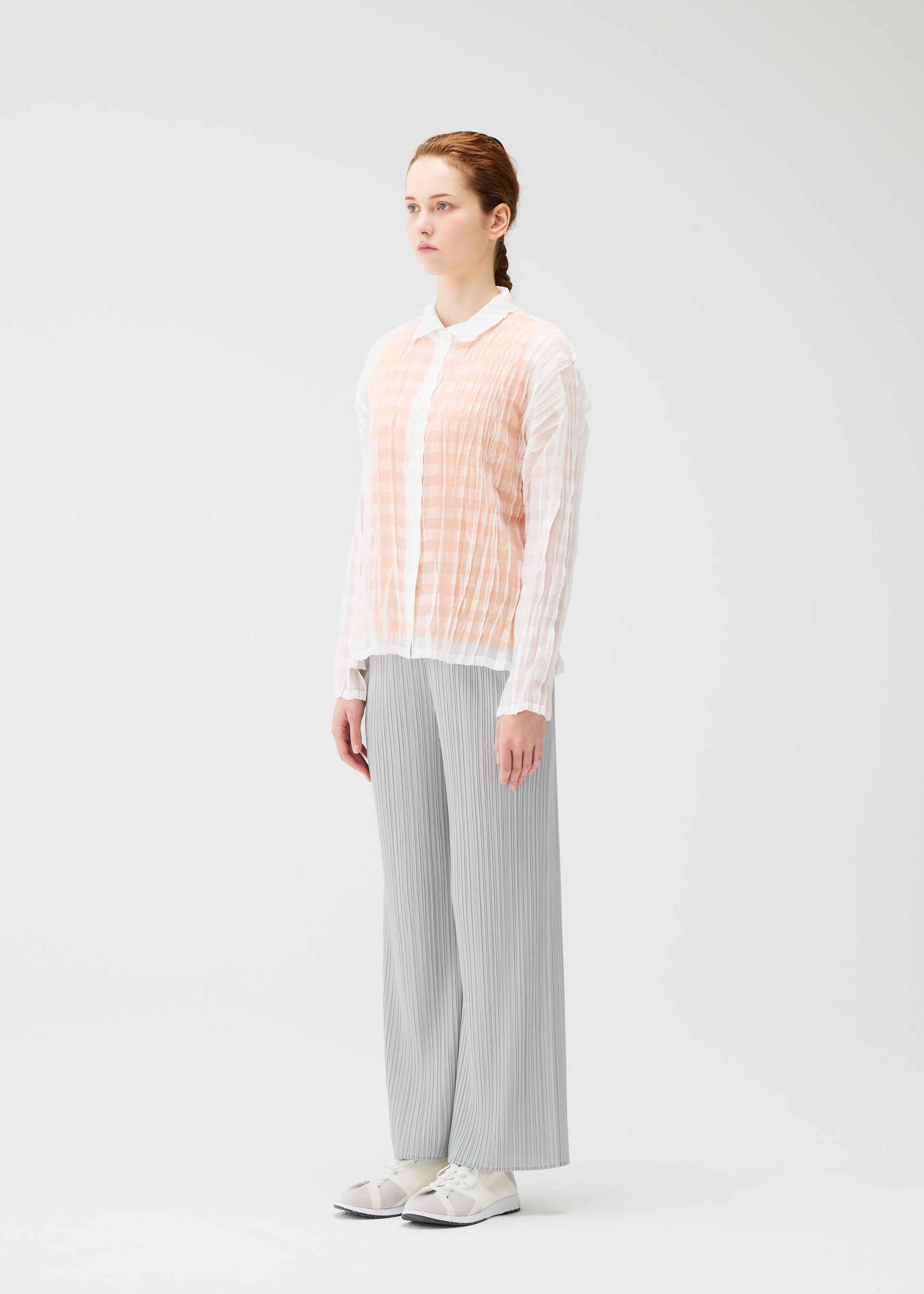 A model wears the PLEATS PLEASE ISSEY MIYAKE TWISTED BORDER SHIRT shirt.