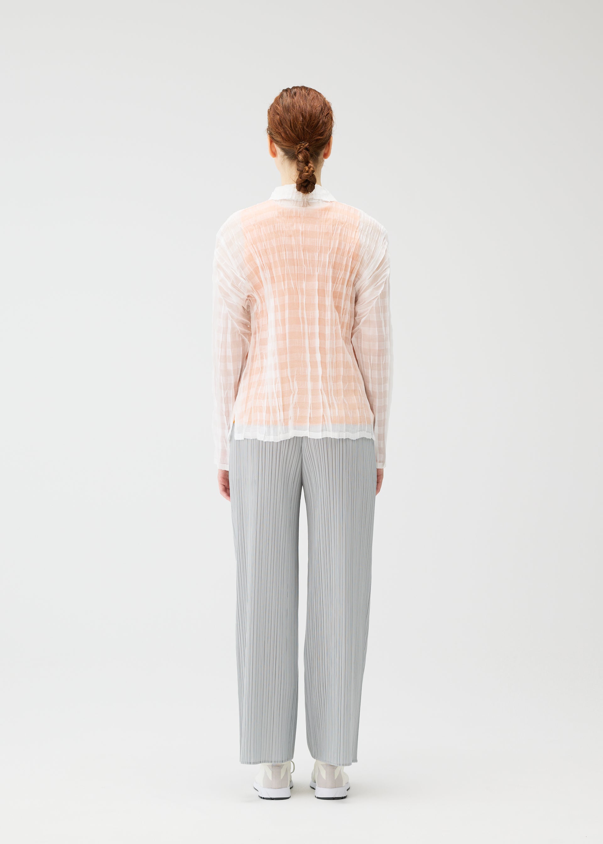 A model wears the PLEATS PLEASE ISSEY MIYAKE TWISTED BORDER SHIRT shirt.