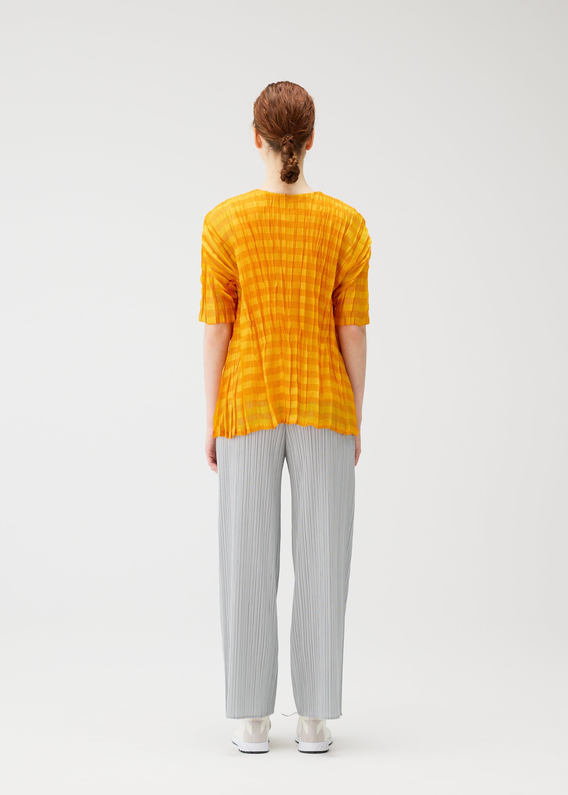 A model wears the PLEATS PLEASE ISSEY MIYAKE TWISTED BORDER SHIRT shirt.