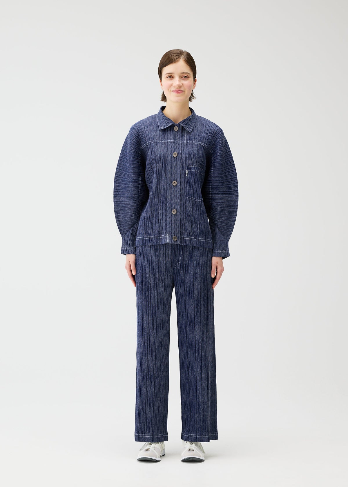 A model wears the PLEATS PLEASE ISSEY MIYAKE COTTON DENIM jacket.