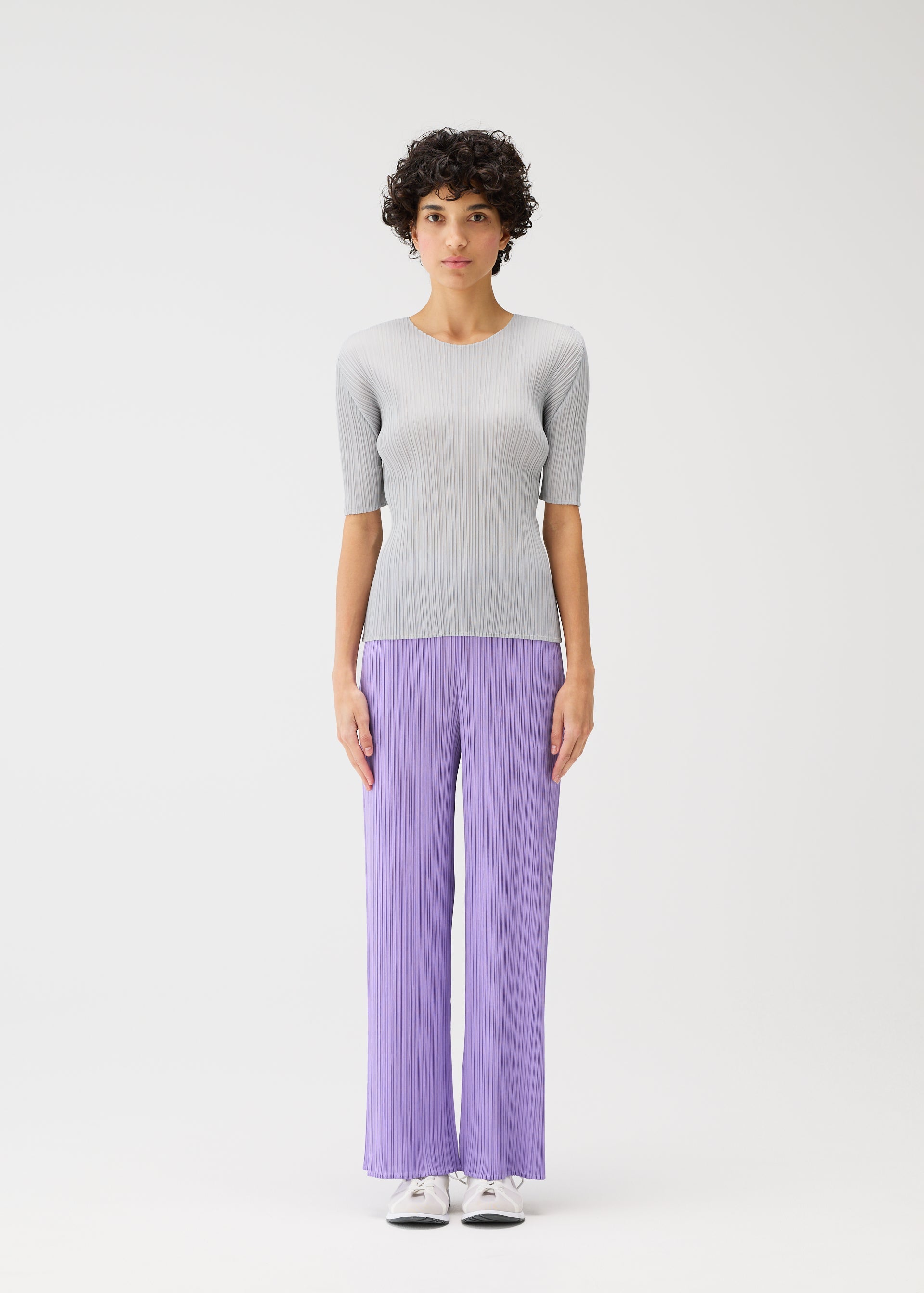 A model wears the PLEATS PLEASE ISSEY MIYAKE MONTHLY COLORS APRIL trousers.