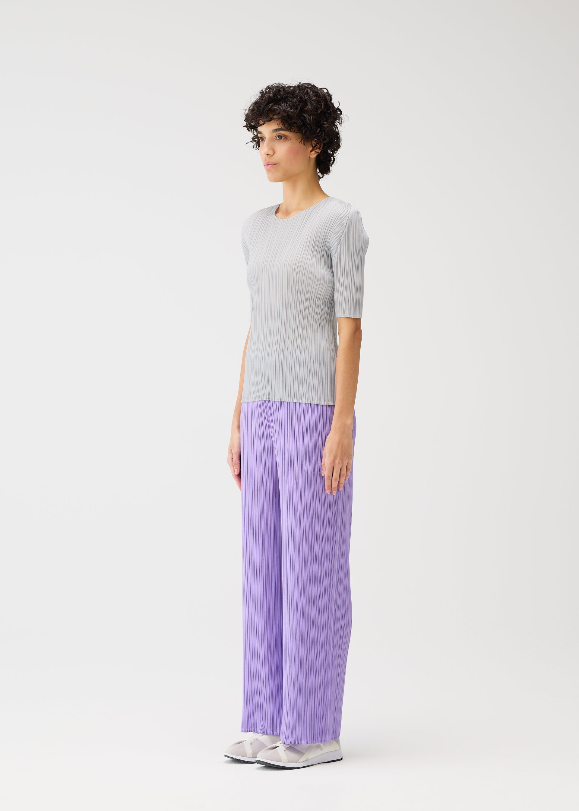 A model wears the PLEATS PLEASE ISSEY MIYAKE MONTHLY COLORS APRIL trousers.
